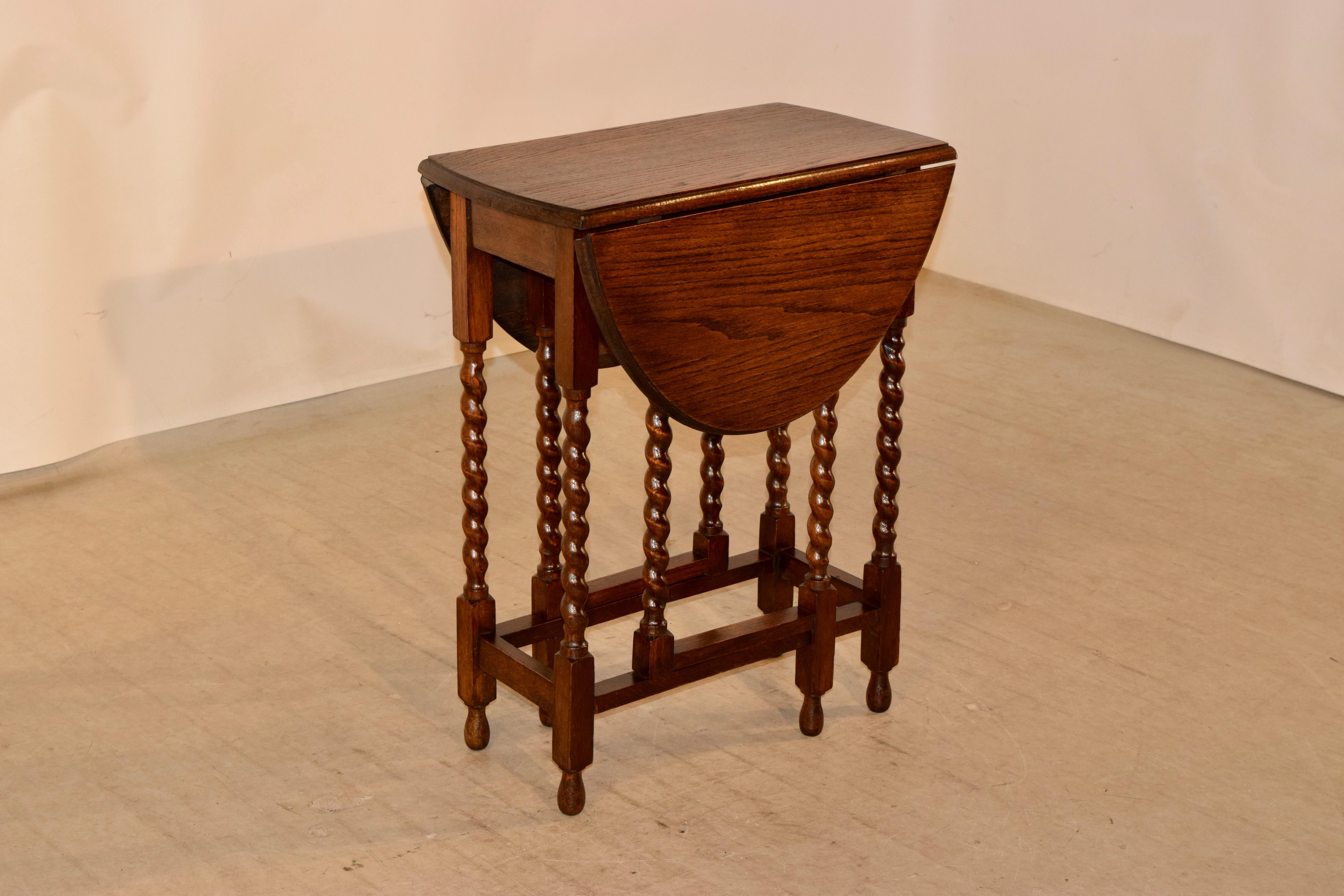 Edwardian period oak gate leg table from England, circa 1900. The top has a beveled edge and follows down to a simple apron. It is supported on hand-turned barley twist legs and gates, all with simple stretchers. The top open measures: 34.38 x 23.5.
