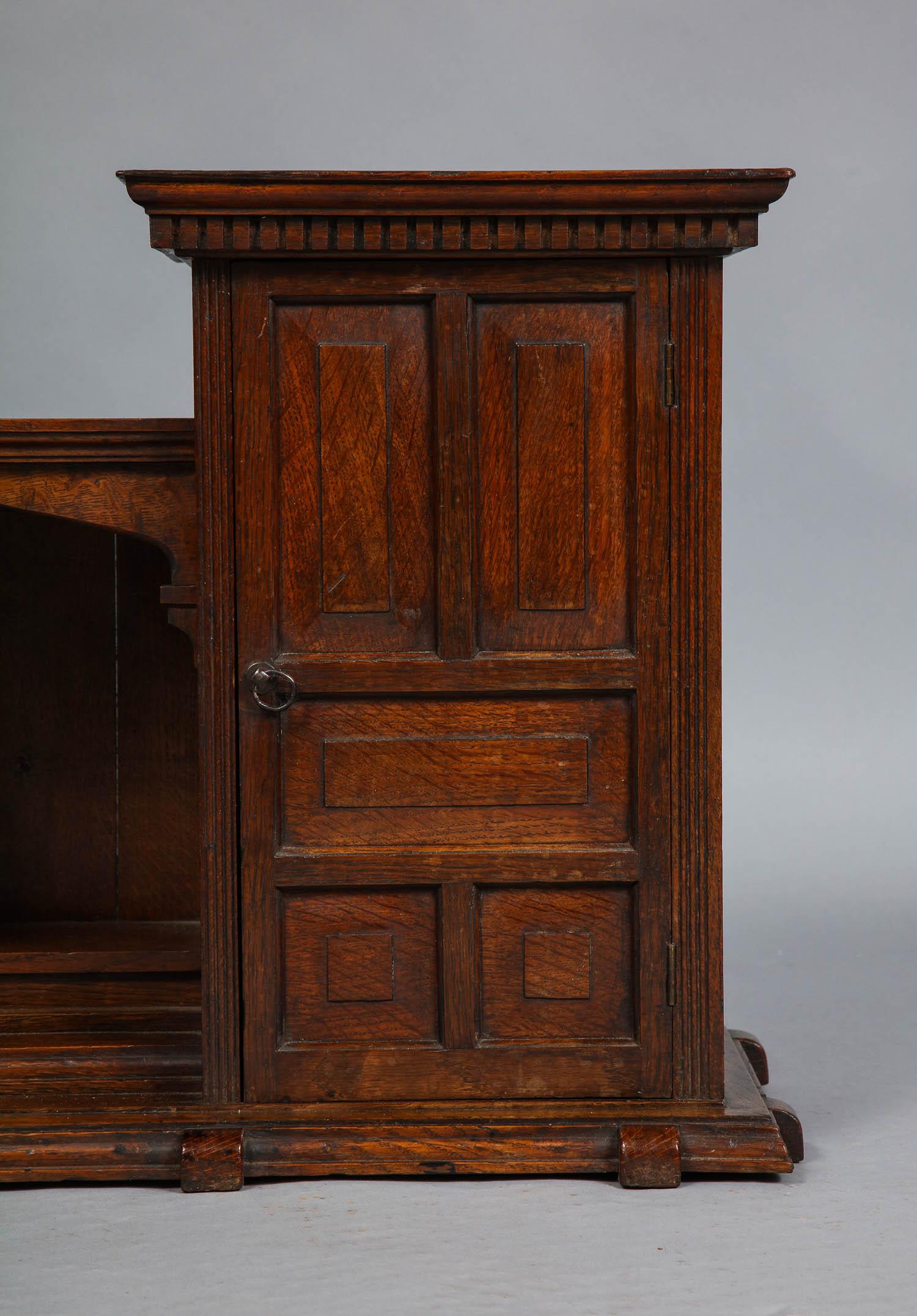 Fine late 19th century English oak hanging or desk cabinet, having two cupboards with paneled doors, dentil molding, and interior shelf flanking open niche with arched cubby, the whole of fine quality. This cabinet would function well either mounted