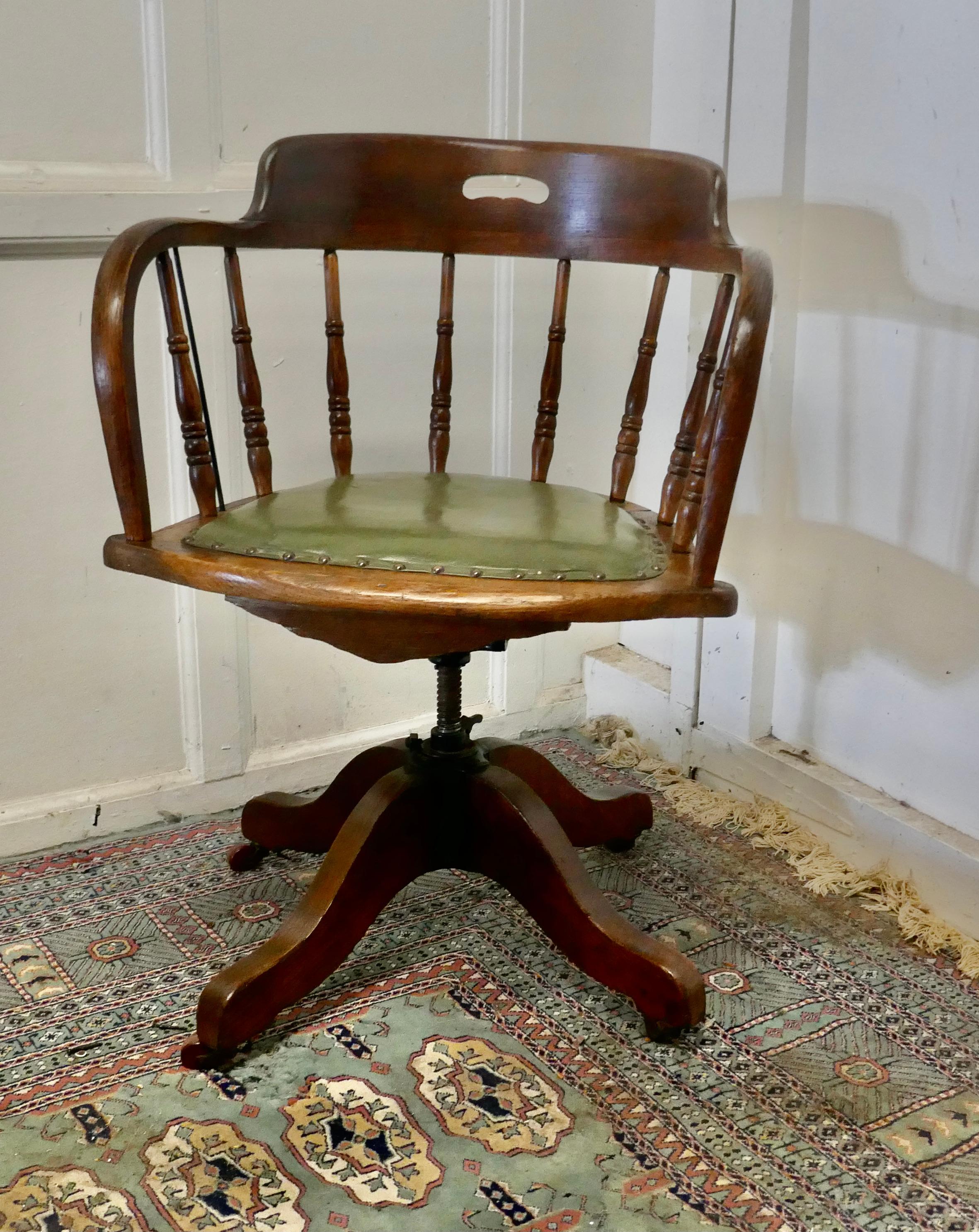 Edwardian oak office desk chair, smokers bow

This office or desk chair has an attractive curving back with a very wide curved top rail and turned spindles beneath, the seat is upholstered in green hide with brass studs
The chair swivels rises