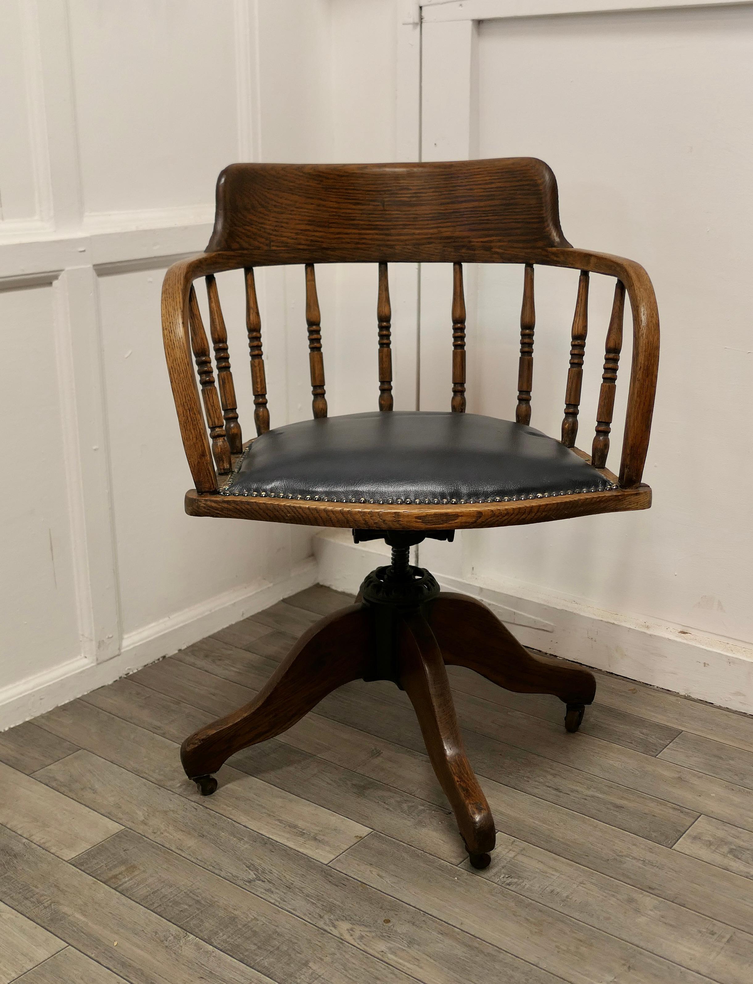 Edwardian oak office desk chair, smokers bow.

This office or desk chair has an attractive curving back with a very wide curved top rail and turned spindles beneath, the seat is upholstered in dark blue hide with brass studs
The chair swivels