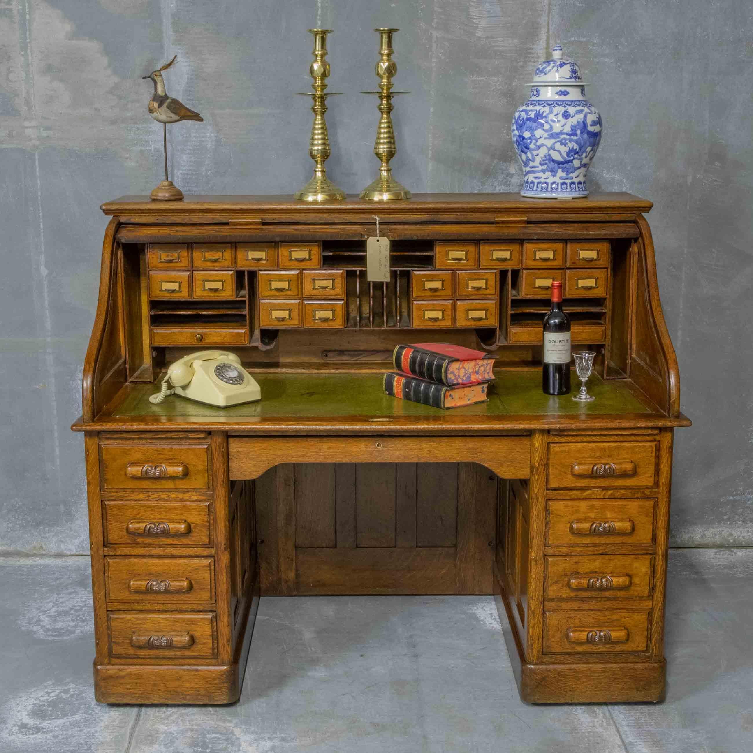 A beautiful Edwardian oak roll top desk of large proportions and with a large width kneehole. The interior is very well fitted with numerous drawers, slides and pigeon holes. The writing surface is of an antique finish olive green leather with gilt