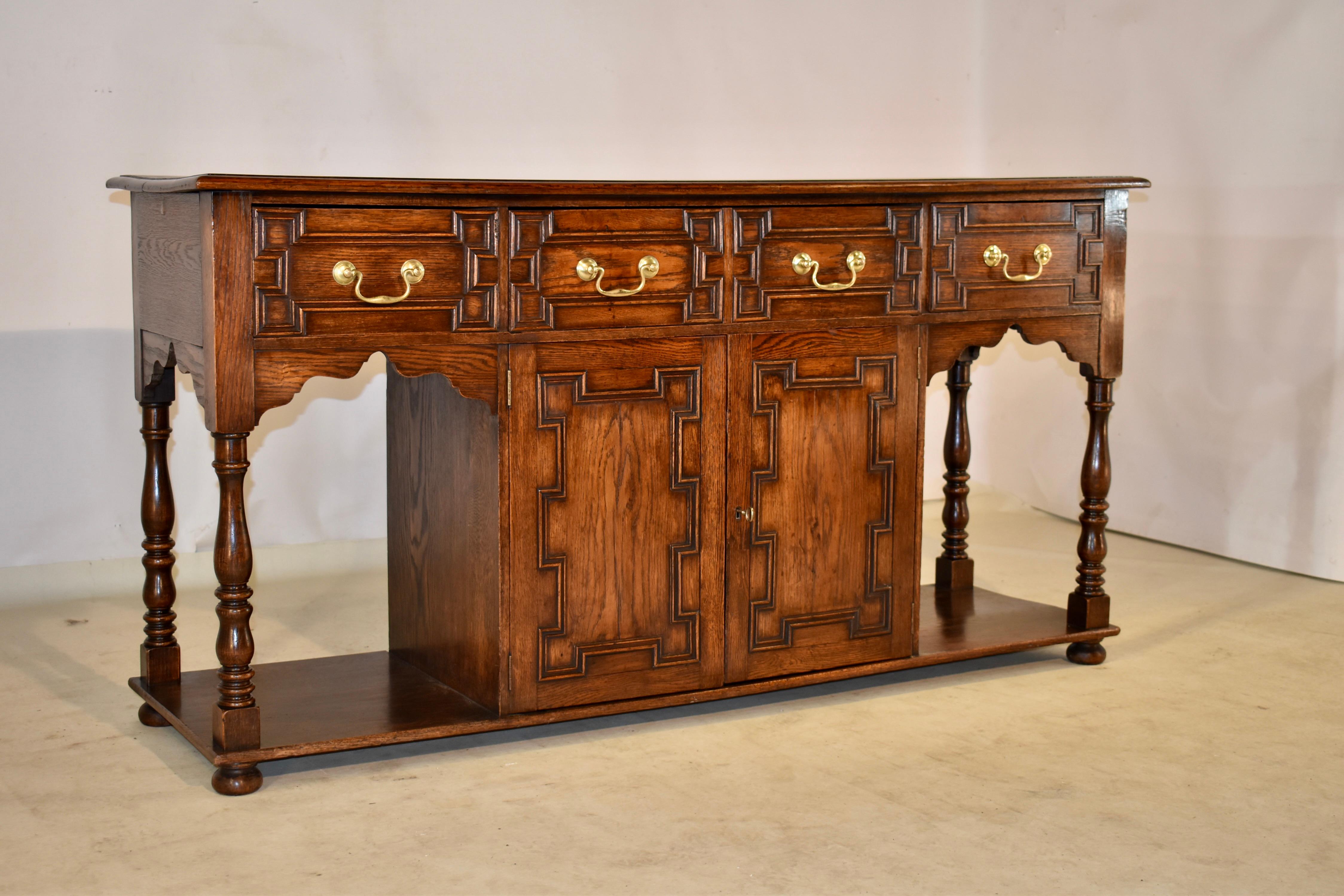 Edwardian oak server from England, circa 1910. The top is wonderfully grained and has a plate rail along the back and a beveled edge. This follows down to simple sides with hand scalloped aprons and three paneled drawers in the front over two doors,