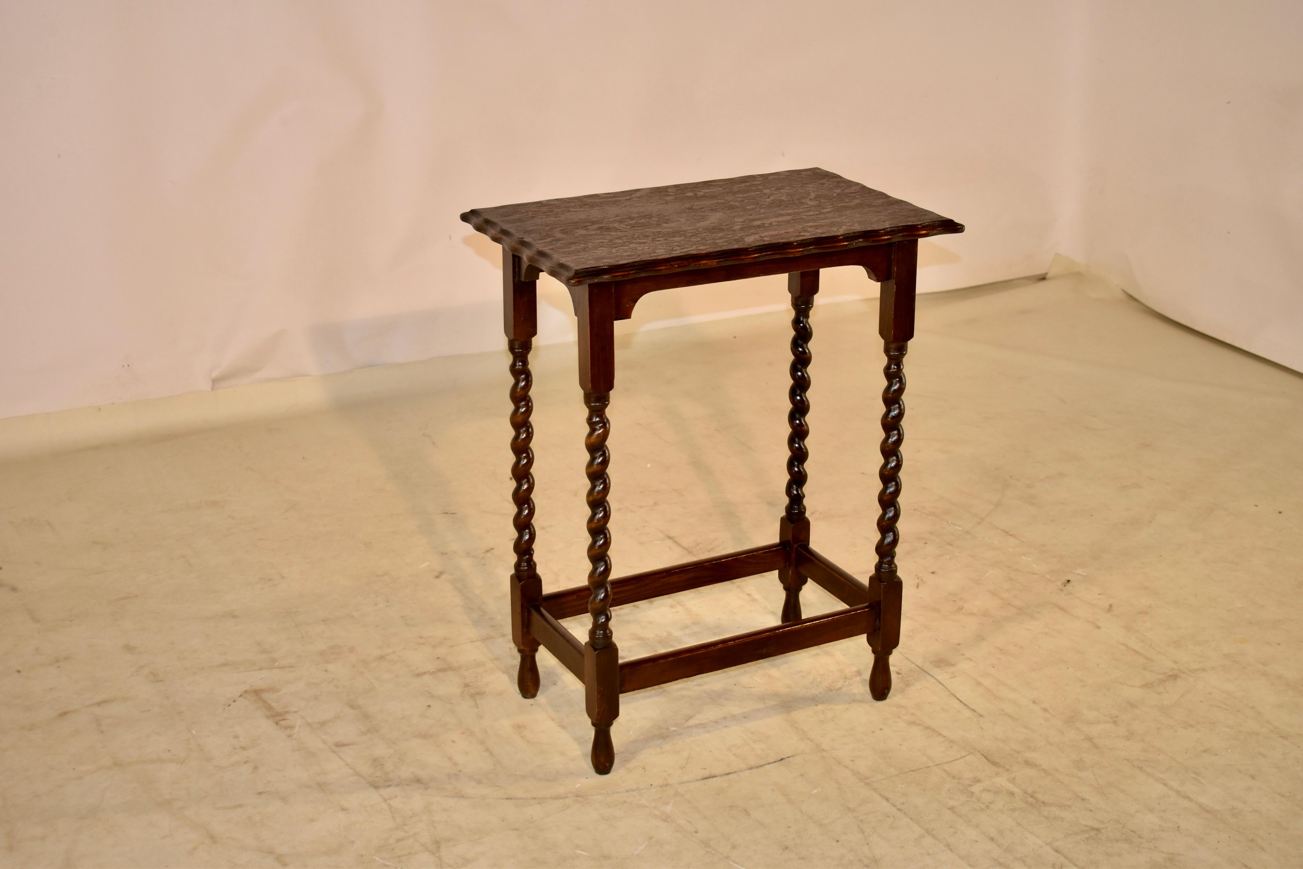 Circa 1900 English oak side table with a scalloped and beveled edge around the top, following down to a hand shaped apron and supported on hand turned barley twist legs. The legs are joined by simple stretchers and the table is raised on hand turned