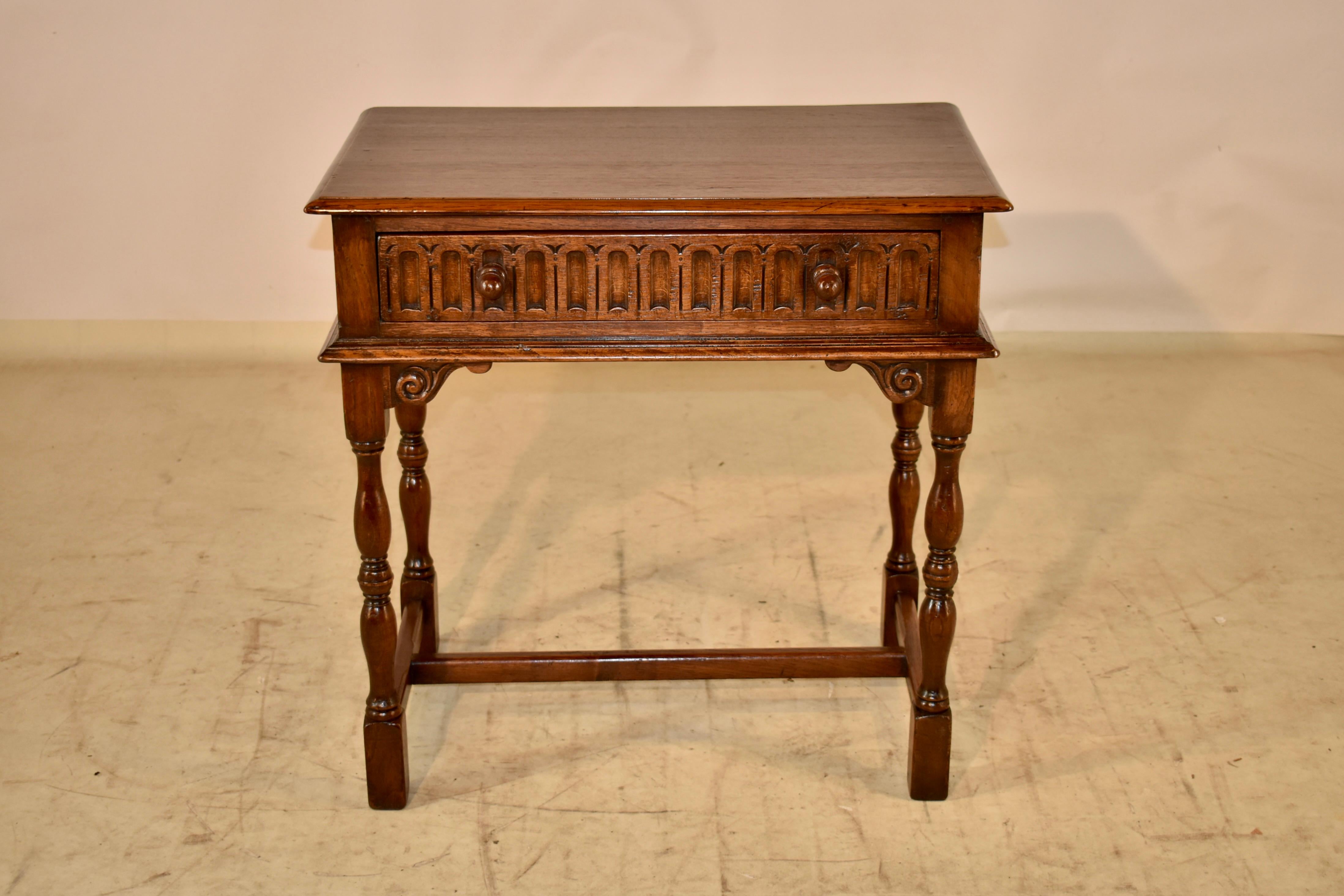 circa 1900 Period Edwardian oak side table from England. The top has a beveled edge, and follows down to a hand carved decorated apron. In the front of the table, the apron contains a single drawer. The table is supported on hand turned legs, joined