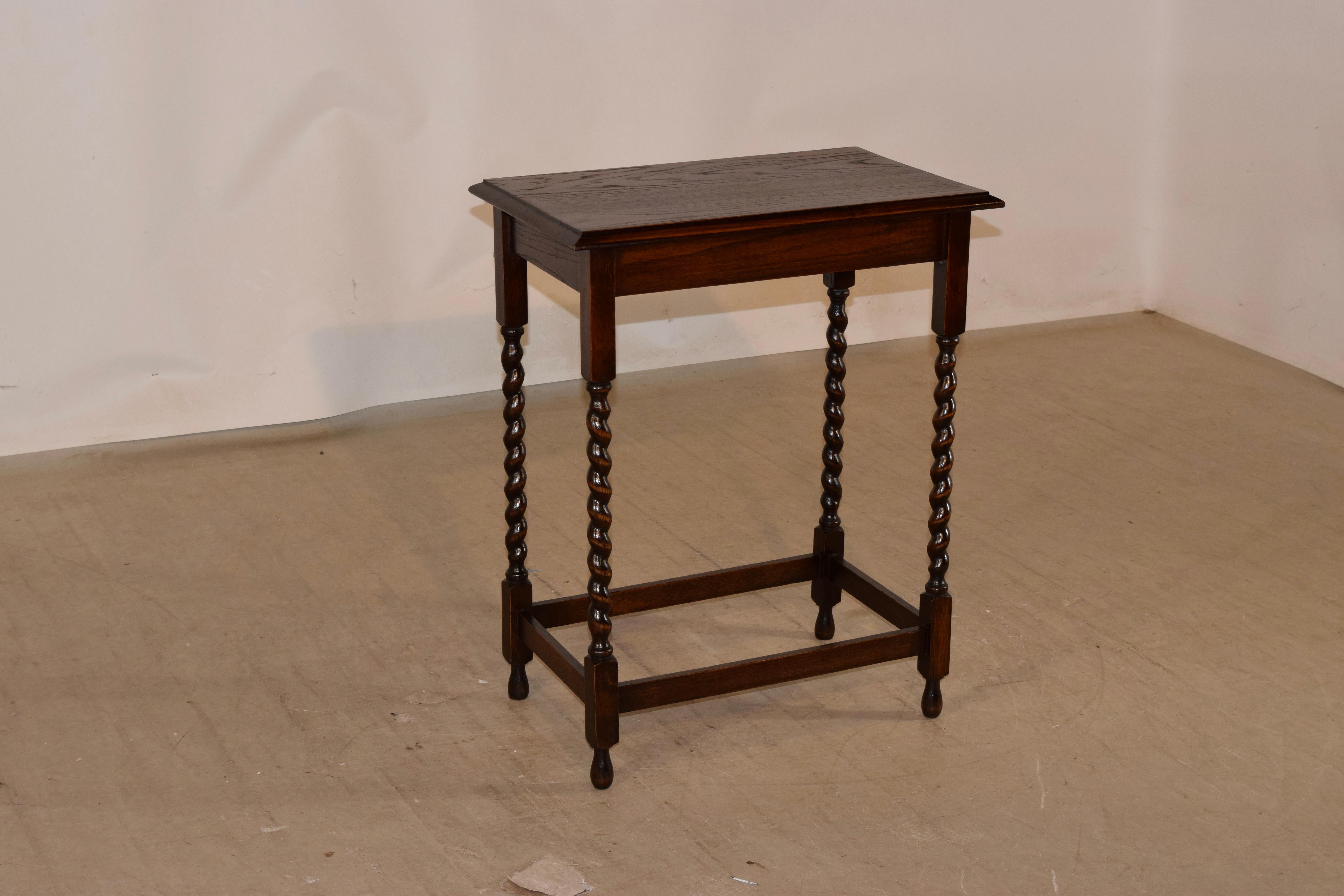 Circa 1900 Edwardian oak side table from England with a beveled edge around the top, following down to a simple apron and supported on hand turned barley twist legs, joined by simple stretchers and raised on hand turned feet.