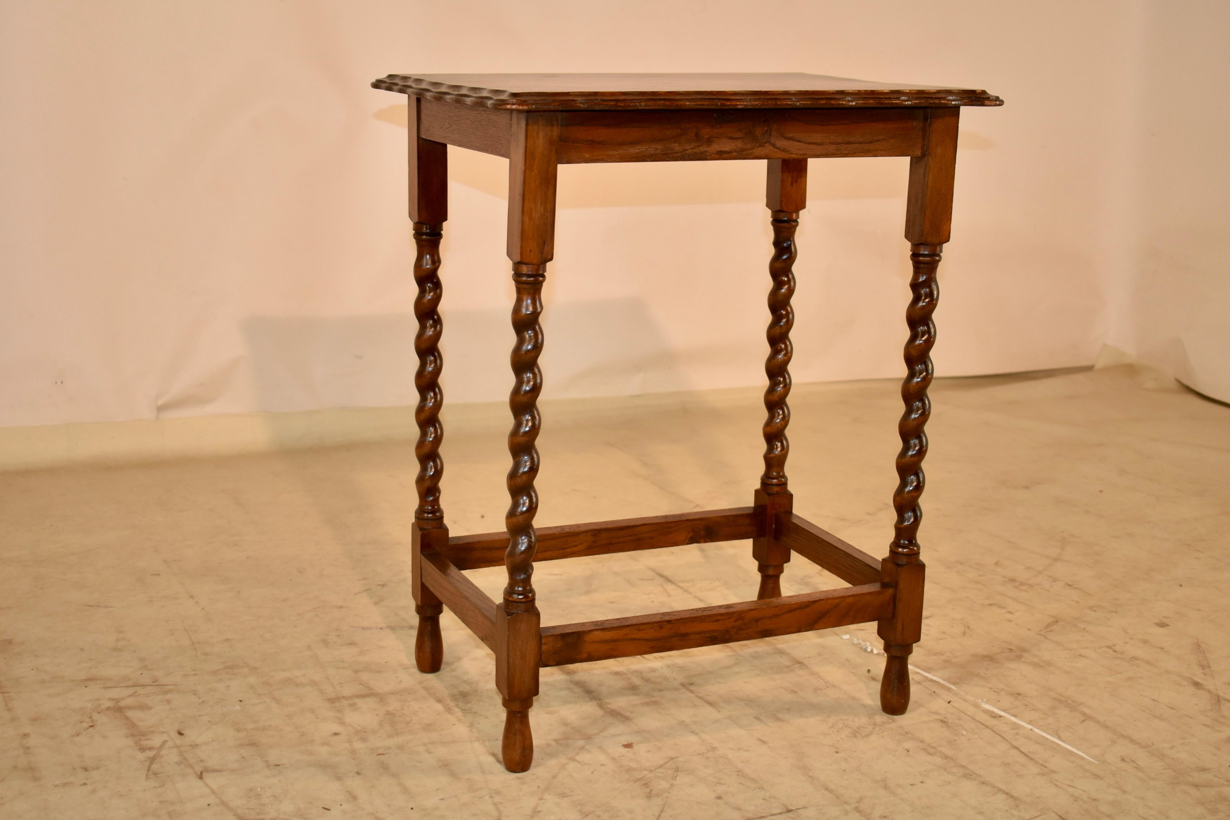 Circa 1900 Edwardian oak side table from England.  The top has an amazing edge.  It is double beveled and scalloped for a stunning appearance.  This follows down to a simple apron and is supported on hand turned barley twist legs, joined by simple