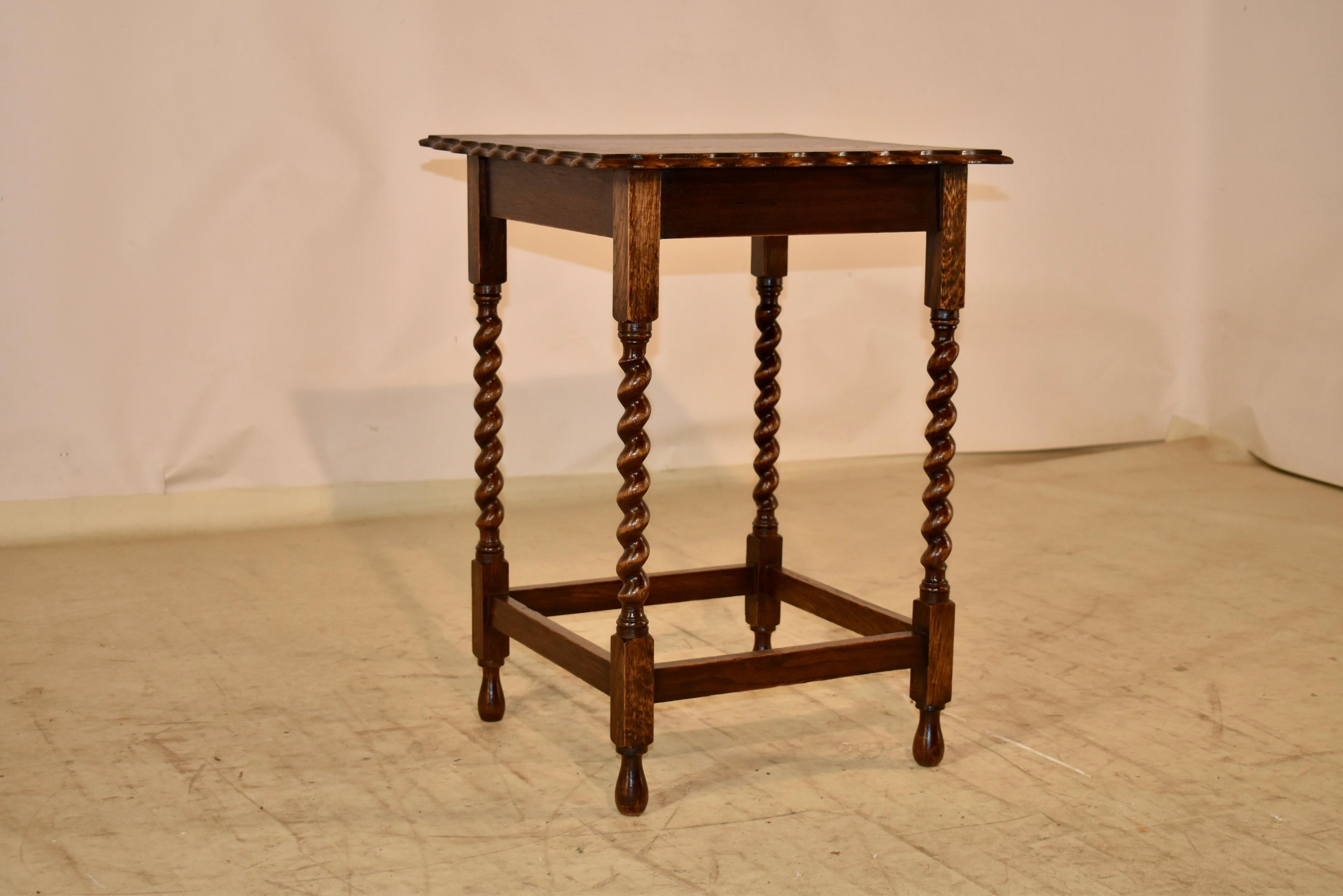 Circa 1900 English oak side table with a lovely hand scalloped and beveled top, following down to a simple apron and supported on hand turned barley twist legs.  The legs are joined by simple stretchers and raised on hand turned feet.