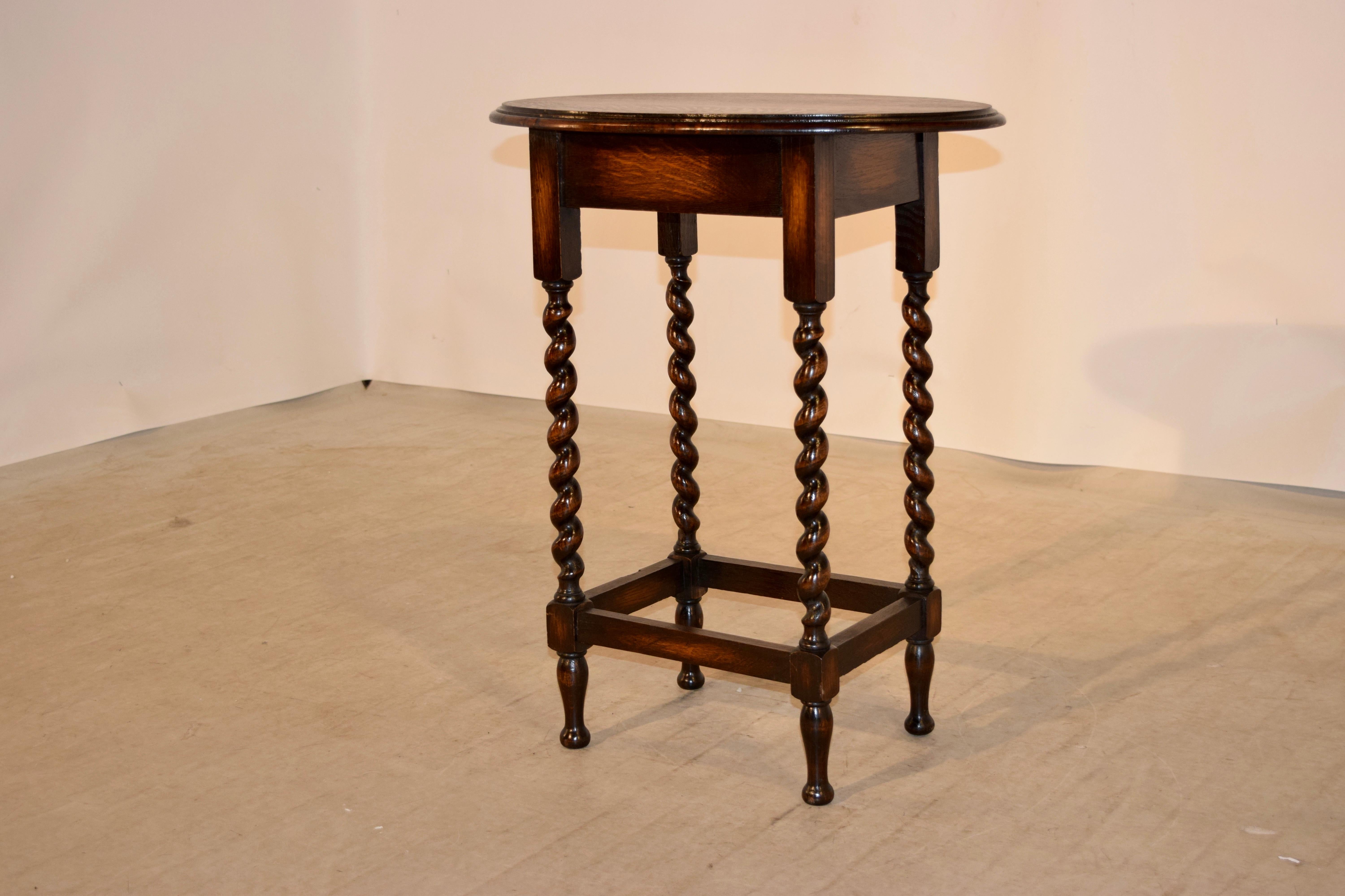 English oak side table with an oval top which has a beveled edge following down to a simple apron and supported on hand turned barley twist legs, joined by stretchers and raised on hand turned feet, circa 1900.