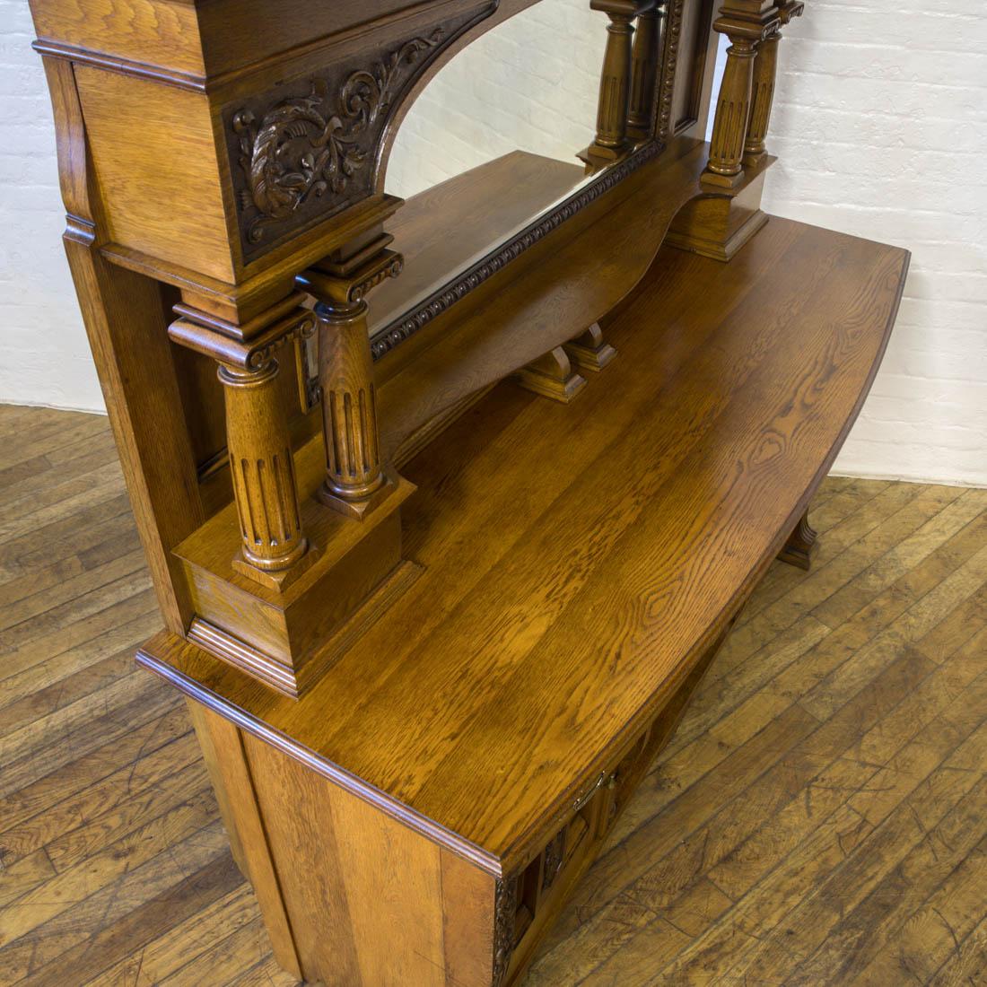 A good quality solid oak mirror back sideboard from the Edwardian period. The dog kennel base has two cupboards with two drawers above. All the carvings to both the top and base are very crisp and much above average quality. Unusual features are the