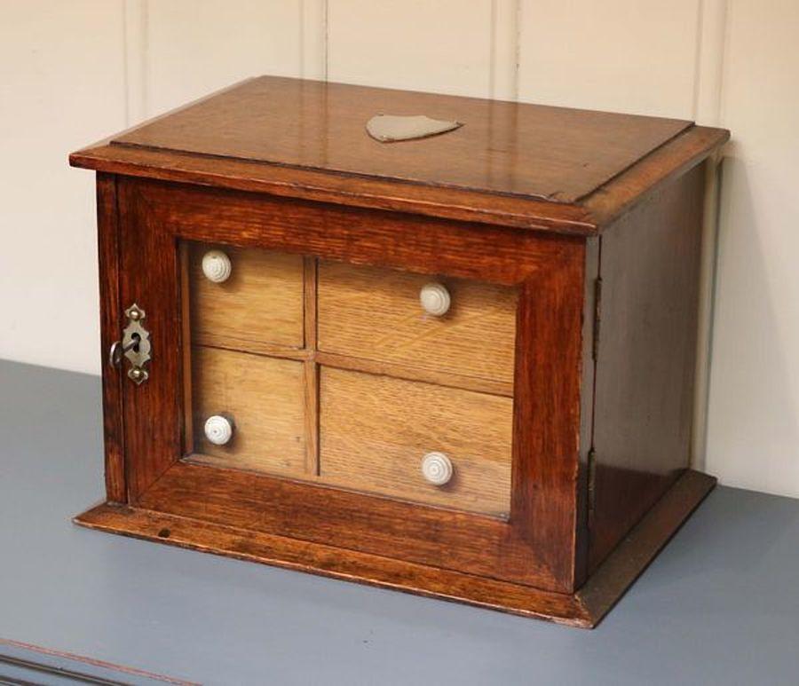 Edwardian oak tabletop collectors box having a single glazed door behind which are four pullout / pull-out drawers with bone handles.