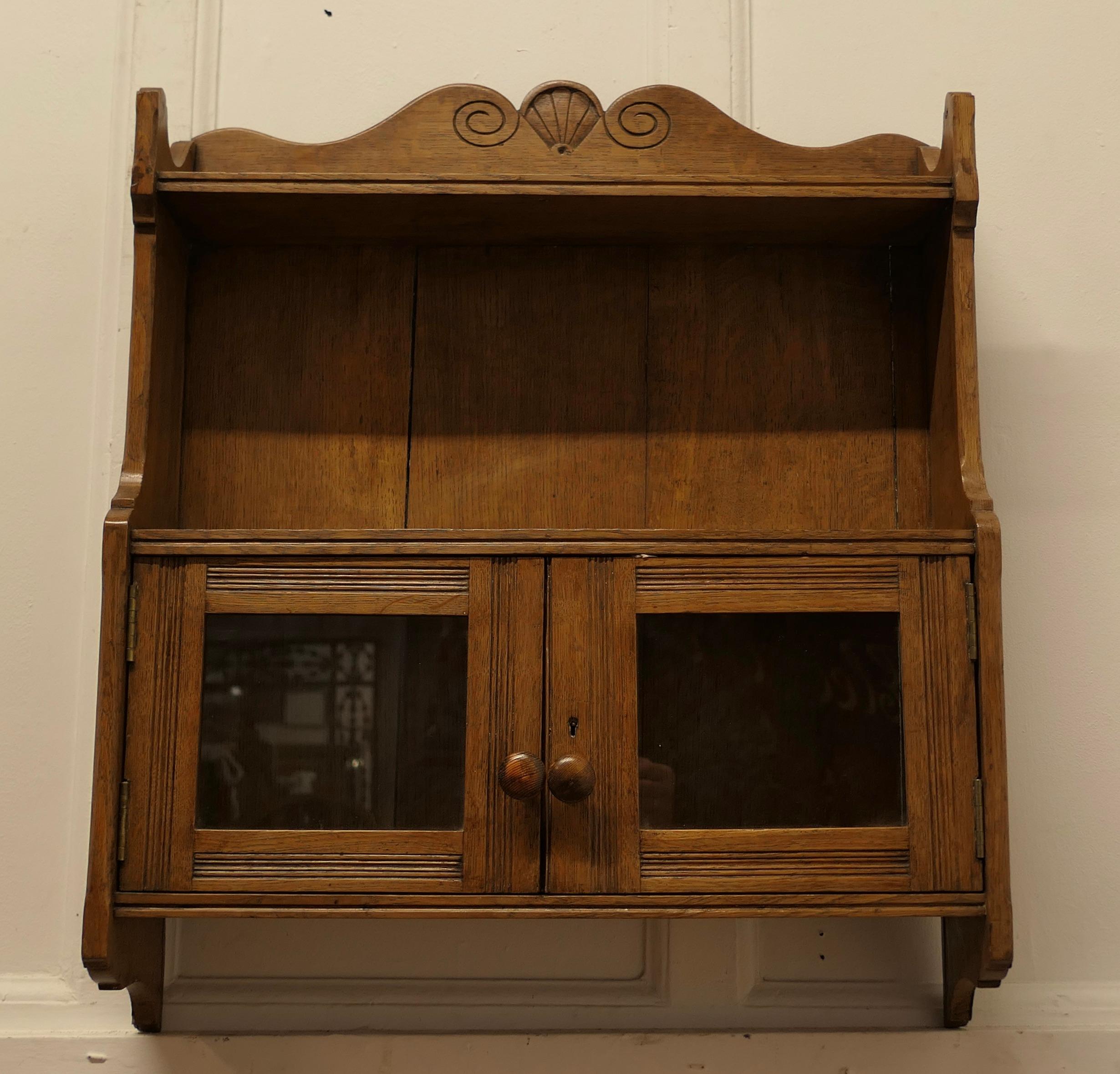 Edwardian Oak Wall Cabinet

A great little piece, made in blonde Oak with a delicate carving to the top  galleried shelf and around the twin glazed doors  
The interior of the cabinet has some tiny water stains otherwise a perfect piece, just the