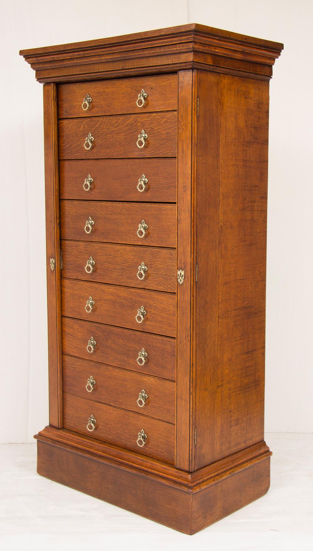 Edwardian Oak Wellington chest of nine drawers with locking bars and secret drawer at back. Working key present and locks working.