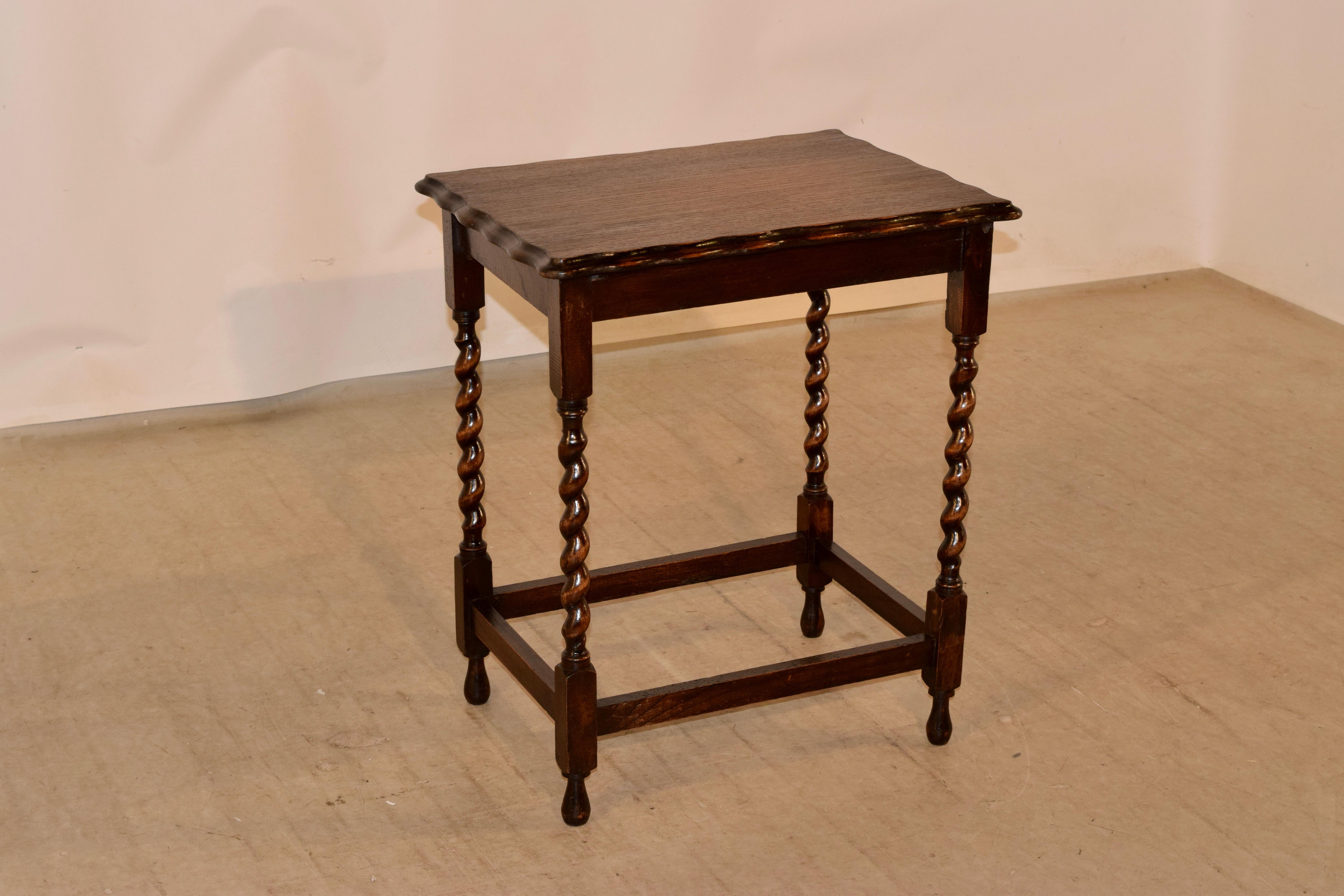 Circa 1900 English oak occasional table with a beveled and scalloped edge around the top, following down to a simple apron and raised on hand turned barley twist legs, joined by simple stretchers and supported on hand turned feet.