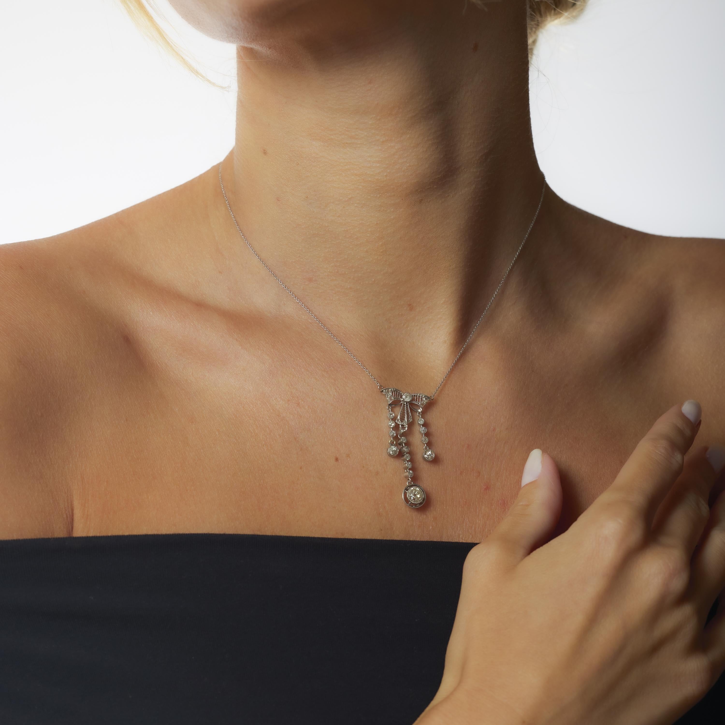 This Edwardian platinum necklace showcases a romantic .85 carat old mine cut diamond, framed by a medley of twenty-two antique accent stones. Crafted in the 1910s with delicate openwork and historic sparkle, it captures the elegance and grace of the