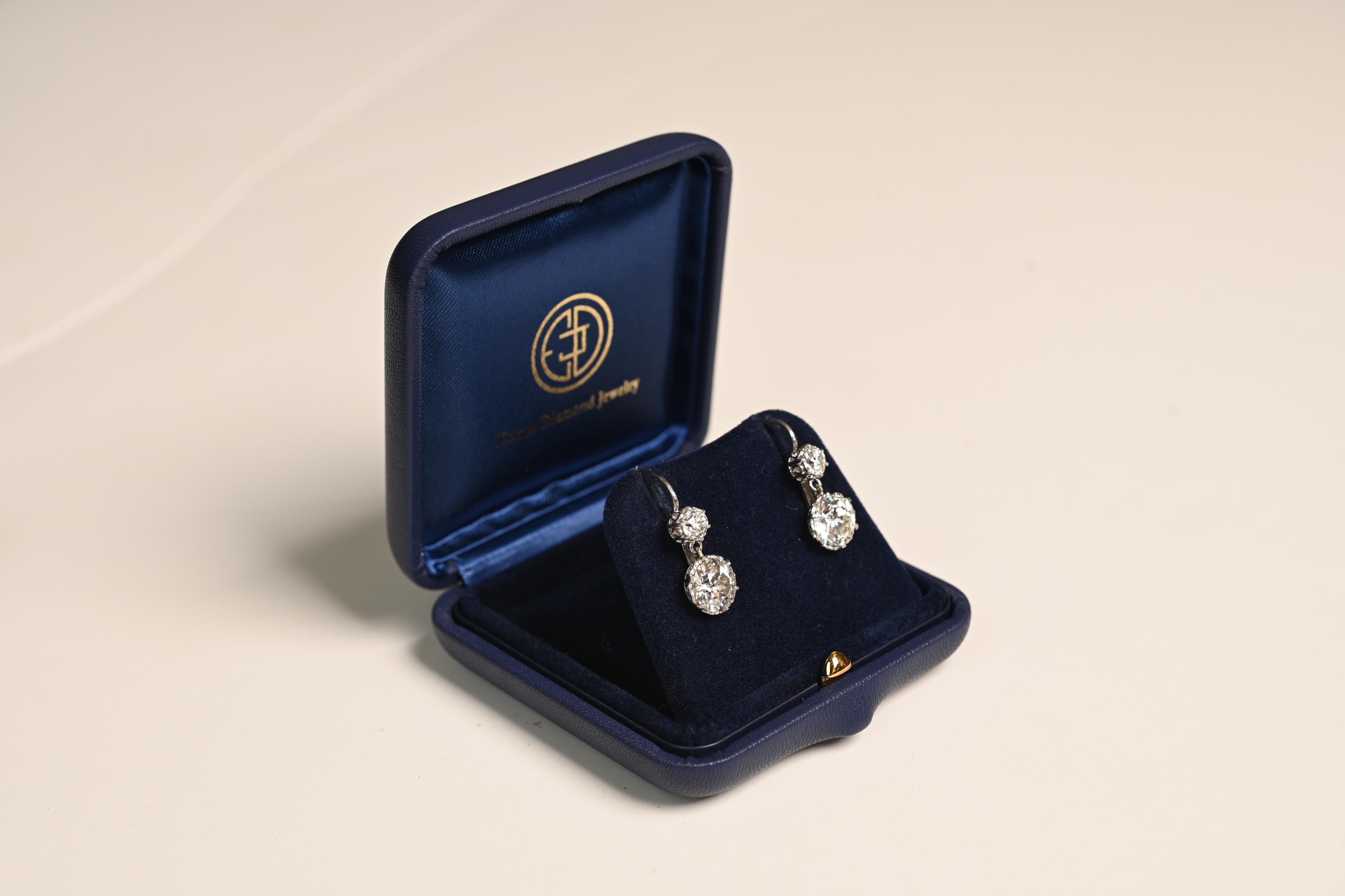 A stunning pair of Edwardian-era drop earrings, circa 1900, crafted in platinum and showcasing the delicate artistry of the period. Each earring features two prong-set old European cut diamonds—cherished for their vintage faceting and distinctive