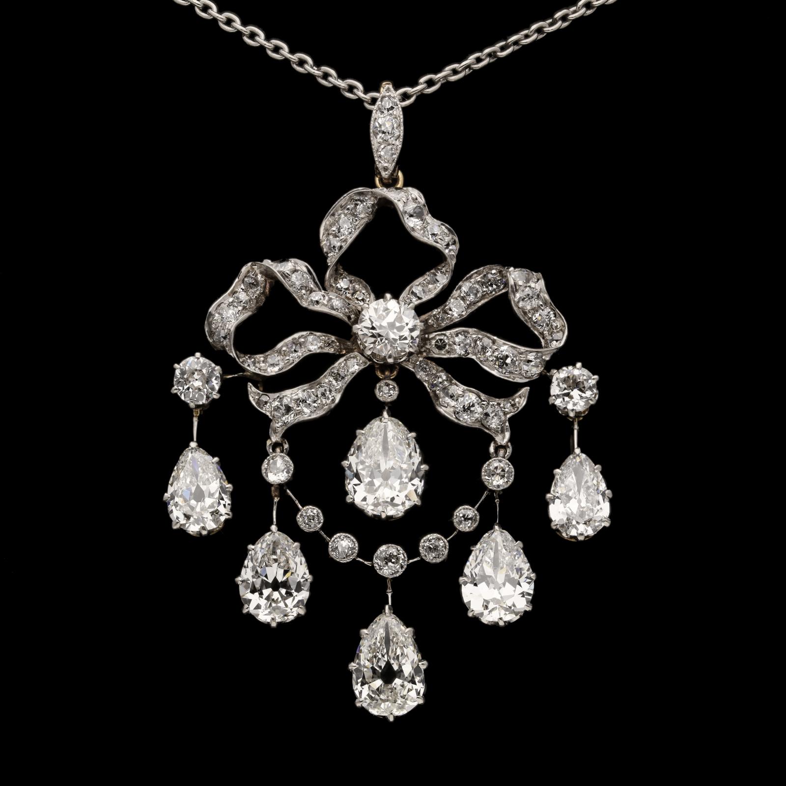 A beautiful Edwardian old mine diamond drop pendant c.1910, of ribbon bow and swag design set throughout with old-cut diamonds and suspending six pear shape diamonds to form an articulated fringe, all in platinum backed with gold and with a fine