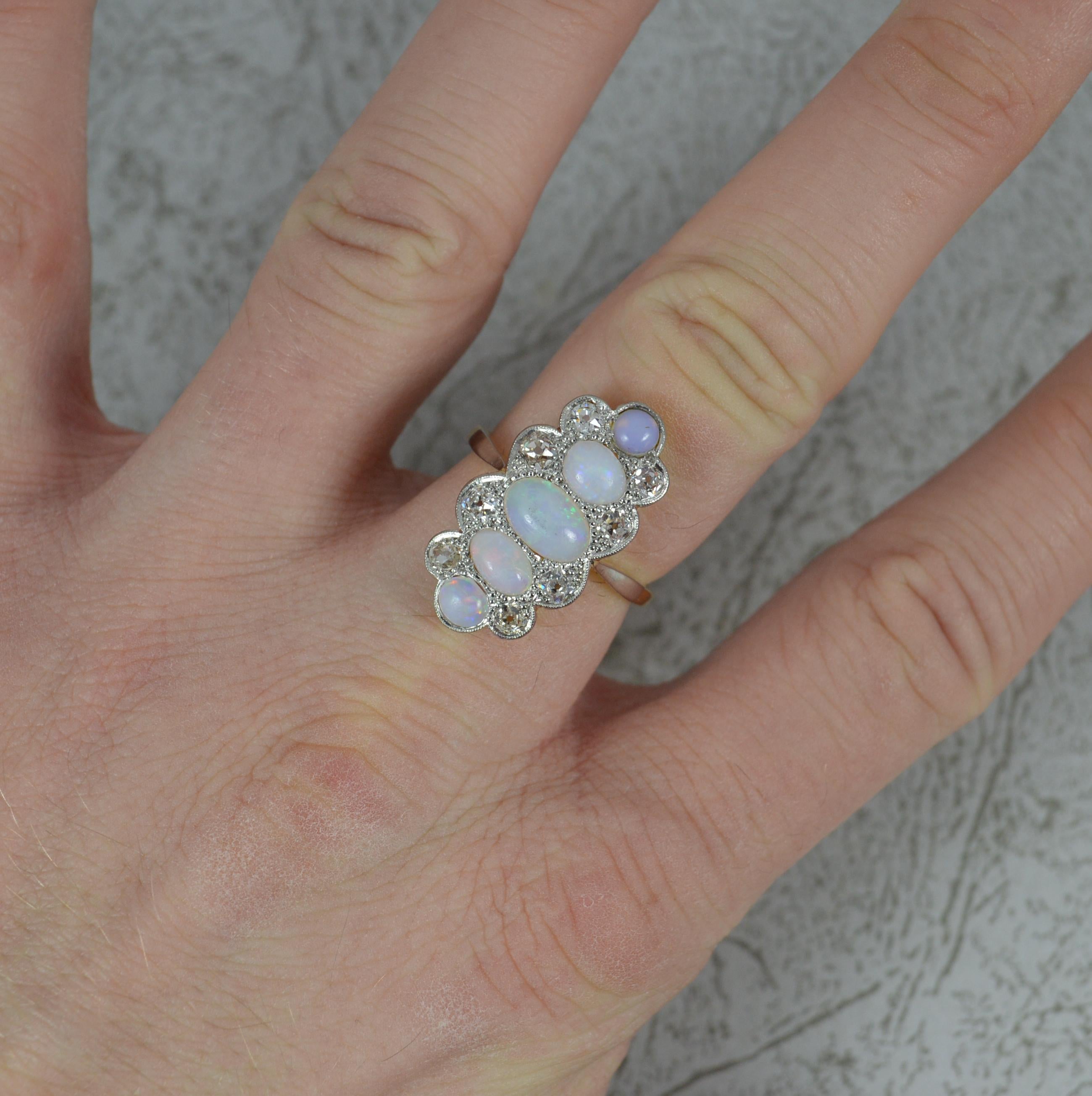 A superb late Victorian or Edwardian era ring.
Solid 18 carat yellow gold shank with a platinum head setting.
Designed with five natural opals of round and oval shapes. To each side are pairs of natural old cut diamonds to the sides. One wonderful