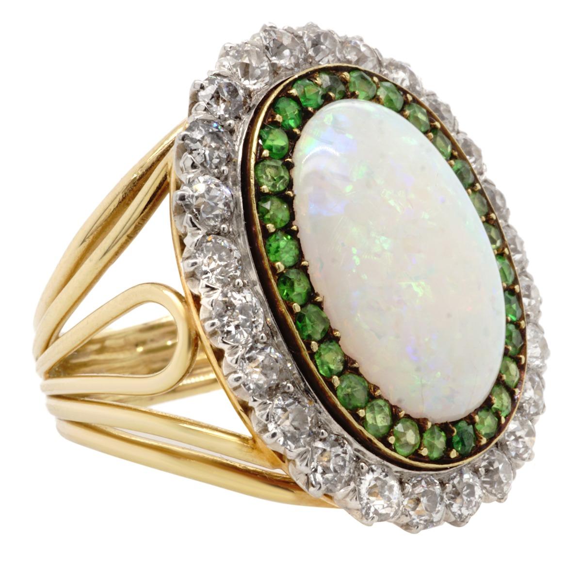 Crafted in 18 karat gold this ring features an oval opal 15.8 x 11.6 mm surrounded by old mine cut diamonds and demantoid garnets.  Weighs 13.0 gr./8.4 dwt.  Ring size 7.

Diamonds:  Estimated weight 2.00 carats
Demantoid:  Weight estimated 1.00