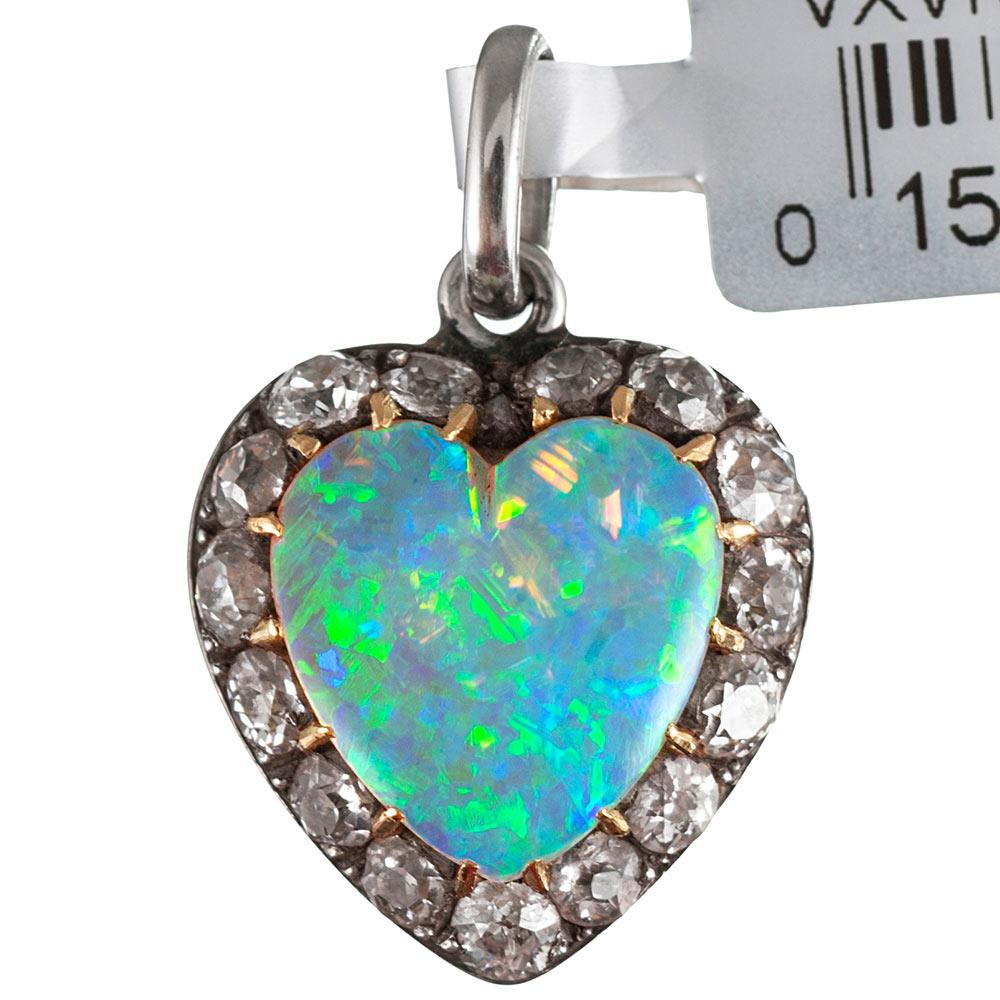 An exceptionally beautiful opal, fashioned into a heart and framed by brilliant antique cut diamonds sits nestled in its antique presentation box. This charming piece conceals at its back a locket, which allows a photo or relic to be contained