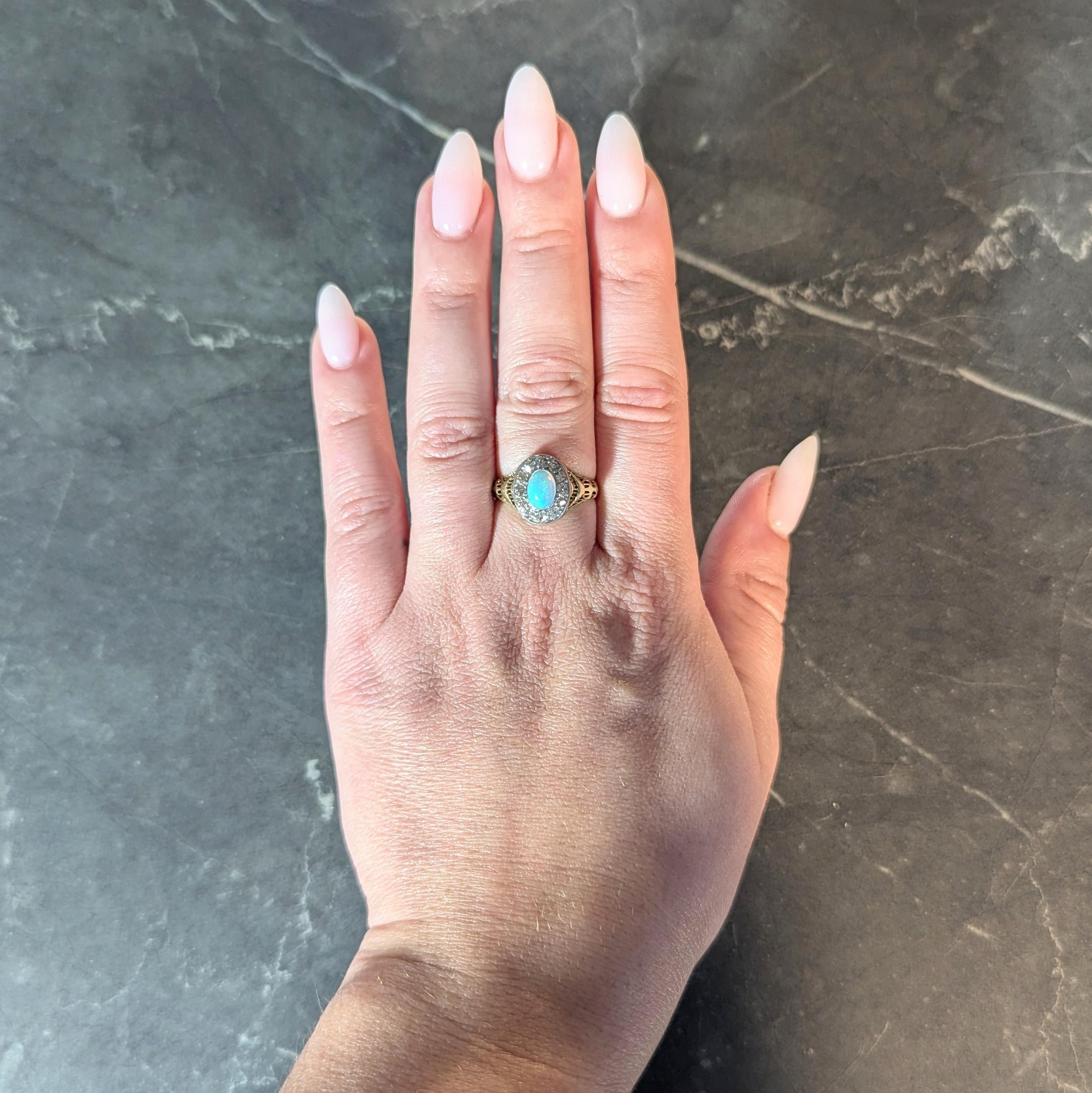 Centering an oval shaped opal cabochon measuring 5.0 x 7.0 mm
Translucent white in body color with spectral play-of-color
Bezel set in platinum with a diamond halo surround
Old European cut and bead set in platinum
Weighing approximately 0.32 carat