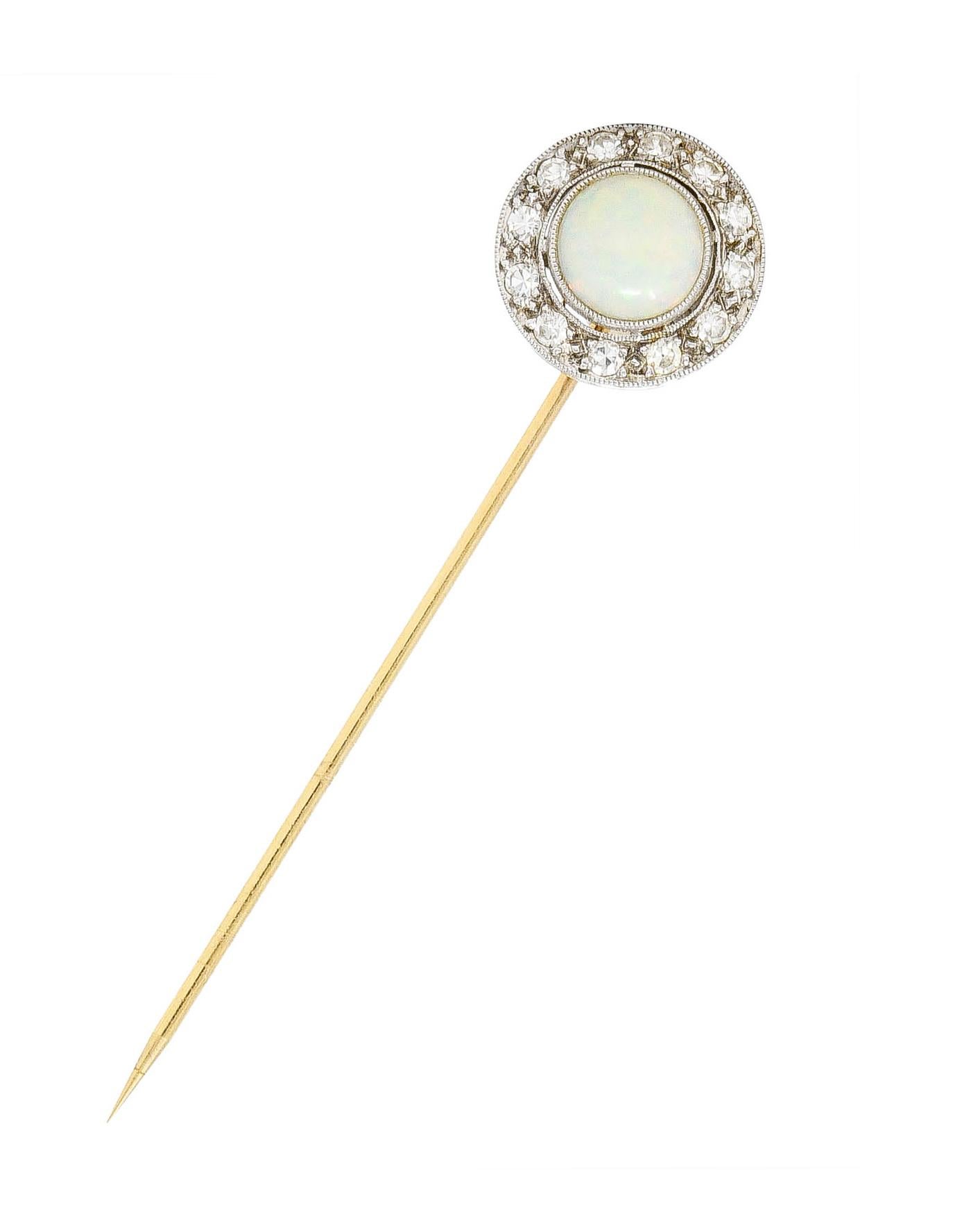 Centering a 6.0 mm round opal cabochon bezel set in platinum

Translucent white in body color with spectral play-of-color

With bead set single cut diamond halo surround

Weighing approximately 0.24 carat total - eye clean and bright

Completed by