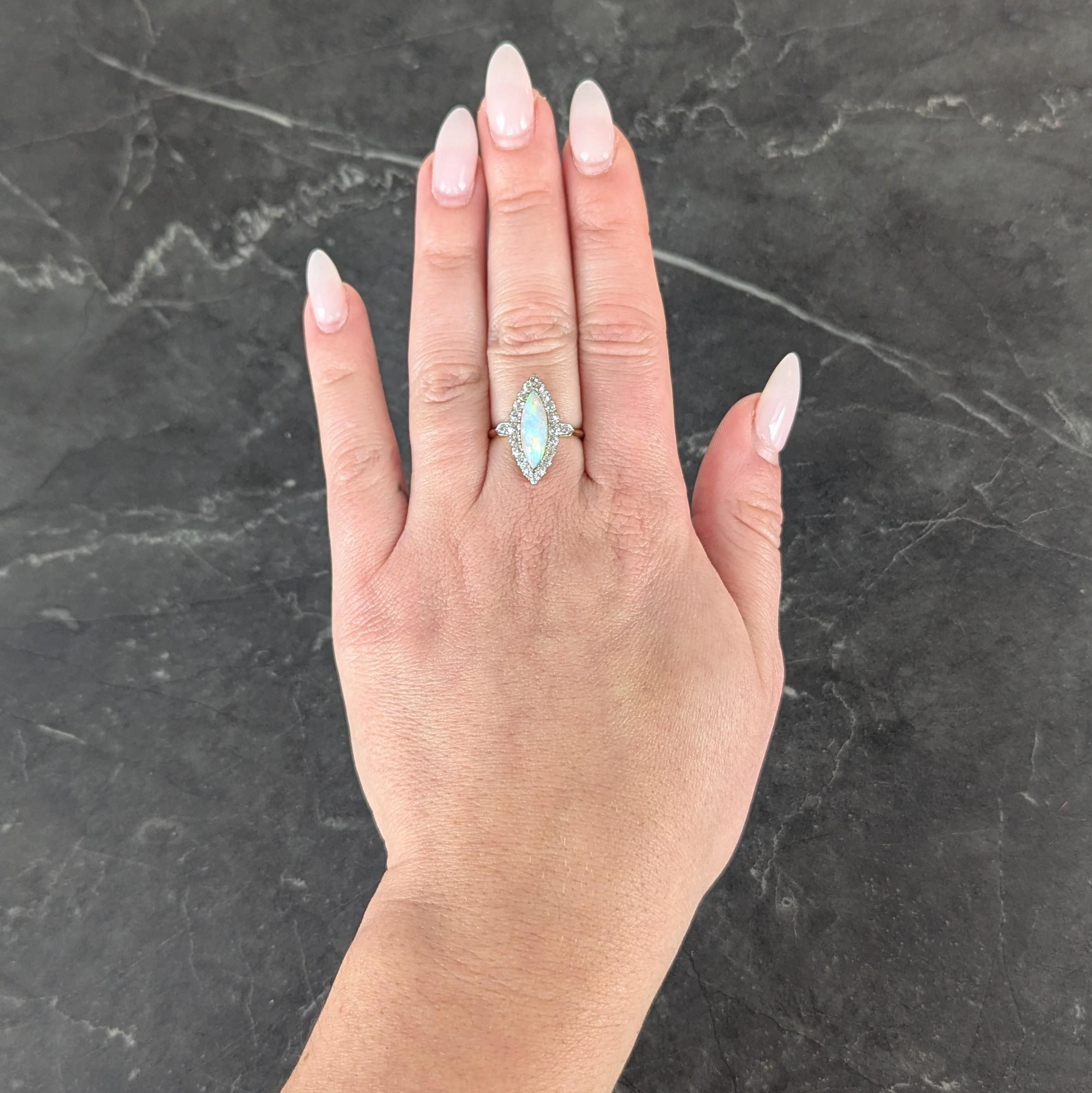 Centering a navette shaped opal cabochon measuring 5.0 x 15.0 mm
White with spectral play-of-color - bead set with halo surround
Platinum-topped and prong set with old European cut diamonds
With additional diamonds bead set in platinum-topped