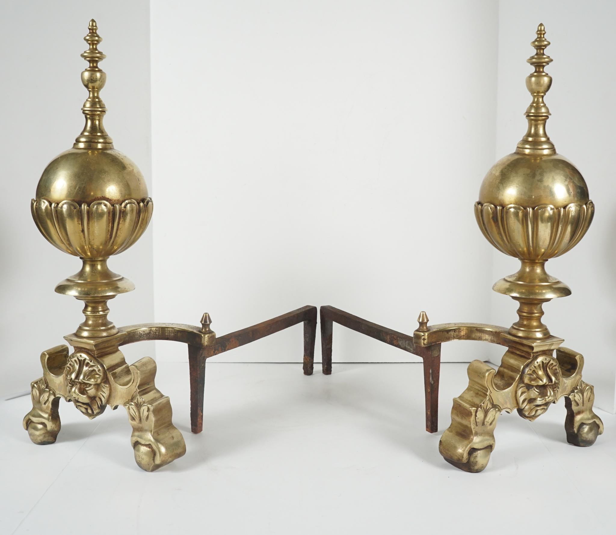 This pair of brass andirons made in England circa 1900 are in an earlier Georgian style. Crafted from heavy castings, the pair has a new polish while being careful to not remove much of the old patina down in the recesses. Attached to hand forged