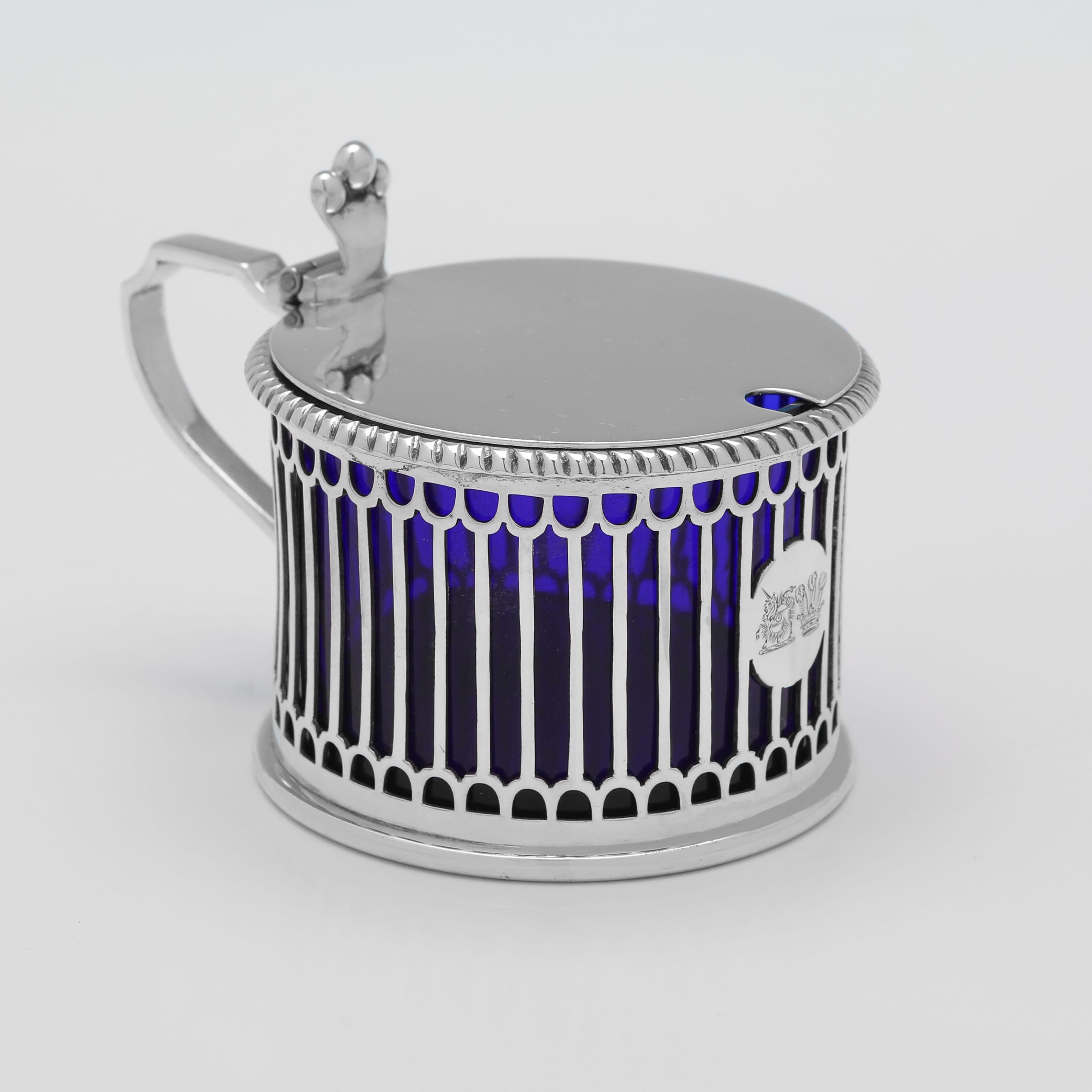 Marcados en Birmingham en 1909 por Elkington & Co., este atractivo par de tarros eduardianos para mostaza, de plata de ley antigua, presentan perforaciones en los laterales, bordes de cuerda alrededor de los bordes, forros de cristal azul y crestas