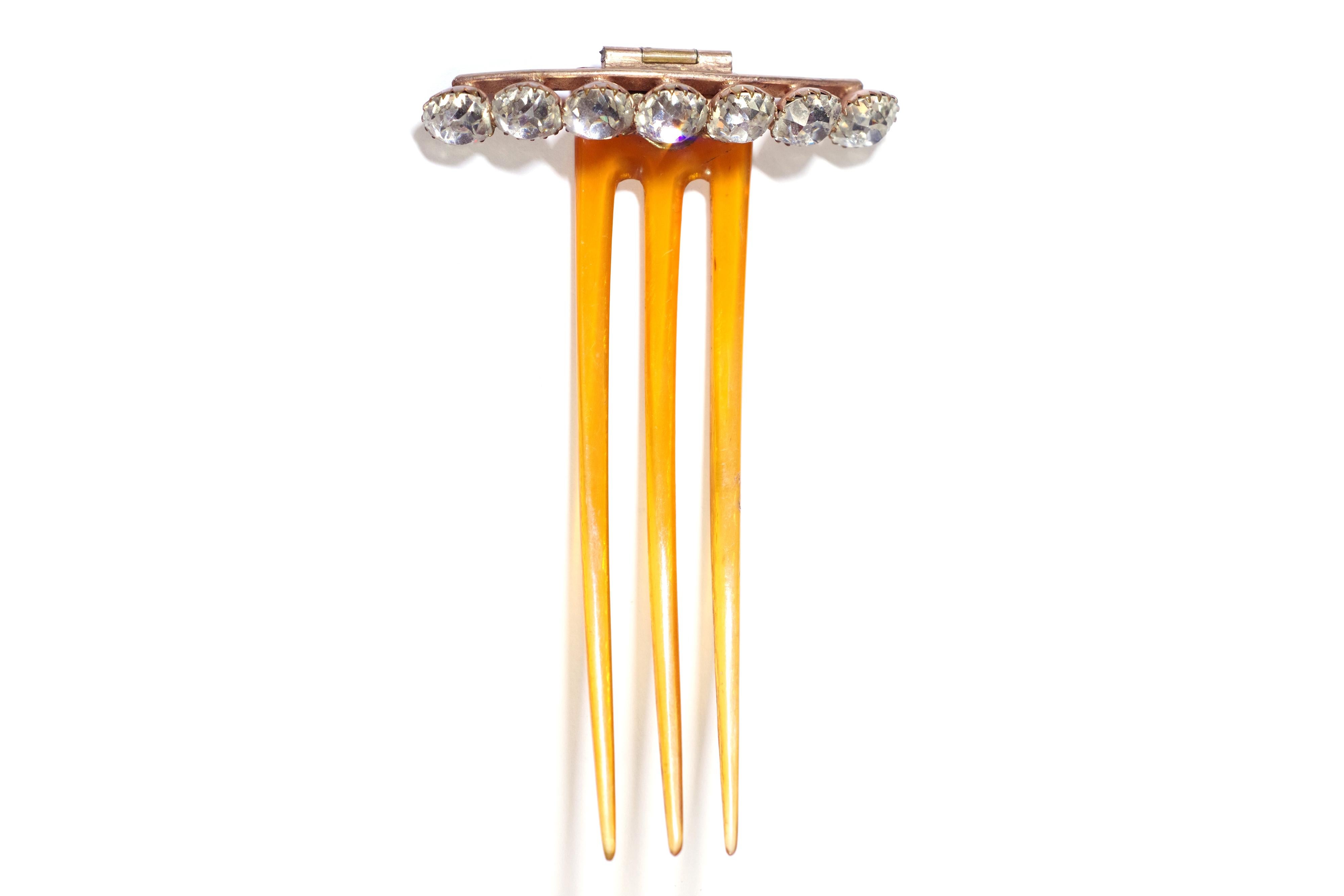 Edwardian paste hair comb made of blonde horn, metal and paste stones. Antique comb with three teeth in horn, the head is organized in a line of  white paste stones in half-moon, set on a gold metal frame. The head of the comb is articulated and
