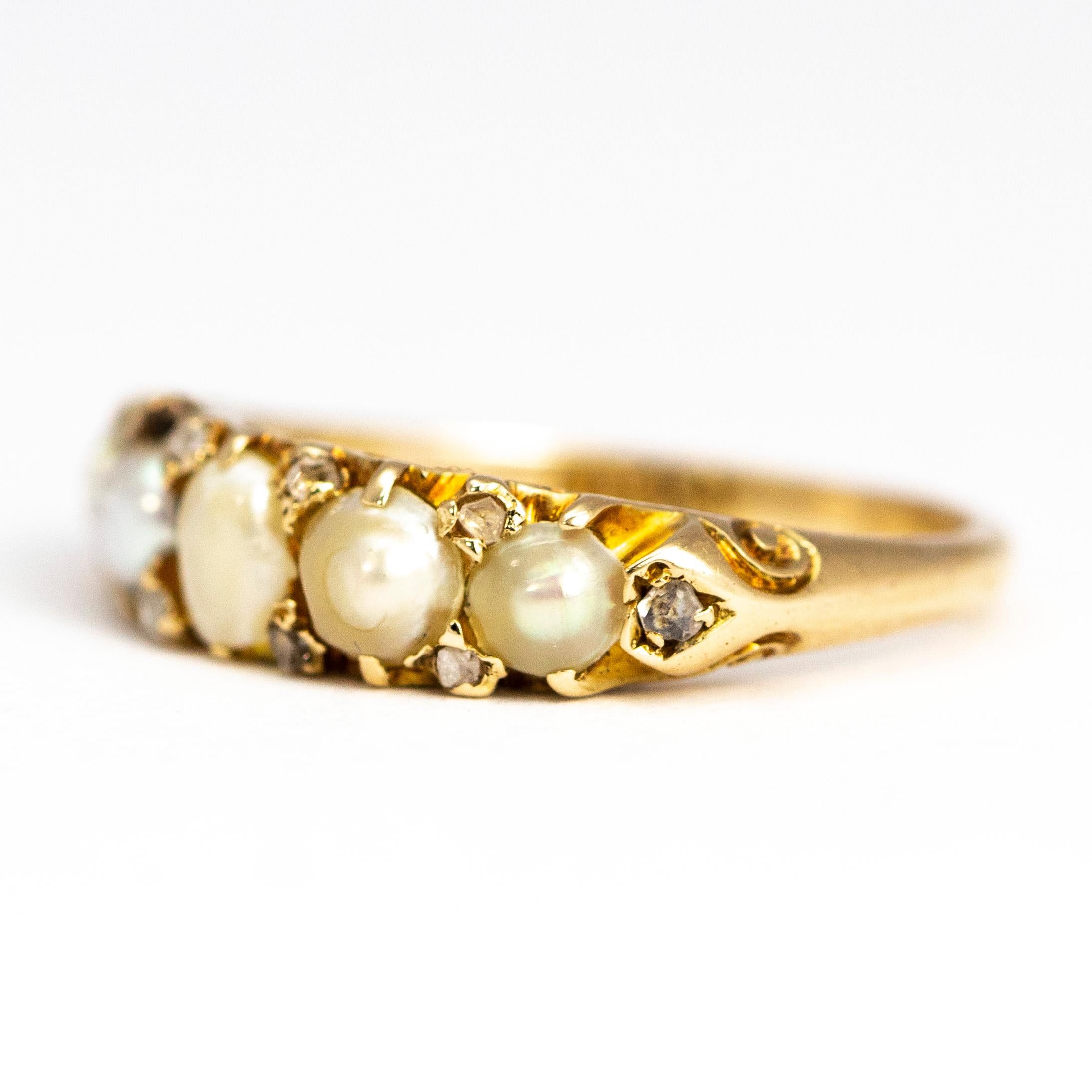 This sweet ring holds a total of five graduated pearls which each have two diamond points in-between them. At either end of the five pearls sits a single rose cut diamond which lead down onto the ornate scroll shoulders. 

Ring Size: L or 5 3/4
Band