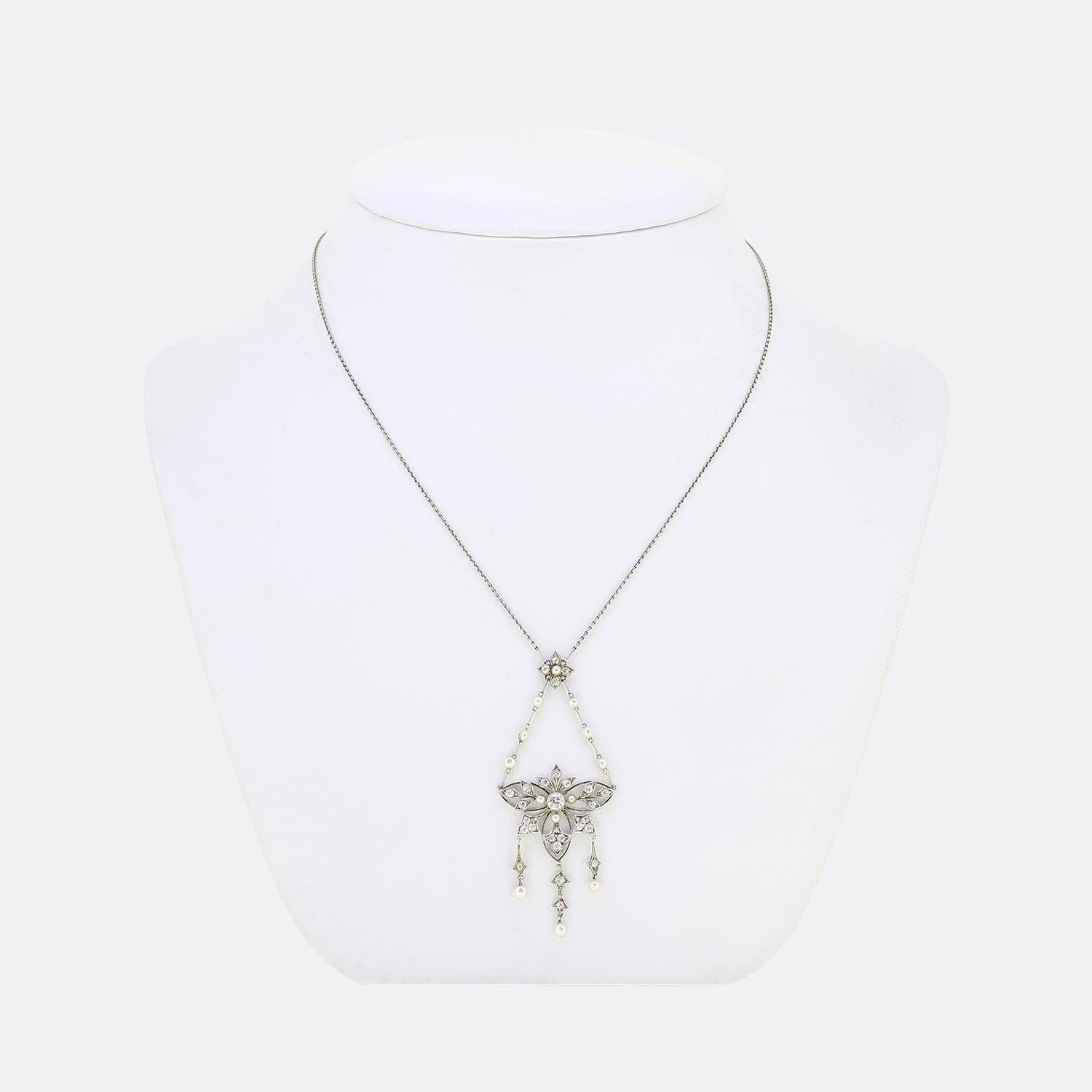 Ecco una deliziosa collana di lavalier risalente all'epoca edoardiana. Una montatura aperta in platino è incastonata al centro con un diamante rotondo sfaccettato di taglio antico, circondato da sei motivi a fiore, ognuno dei quali è incastonato con