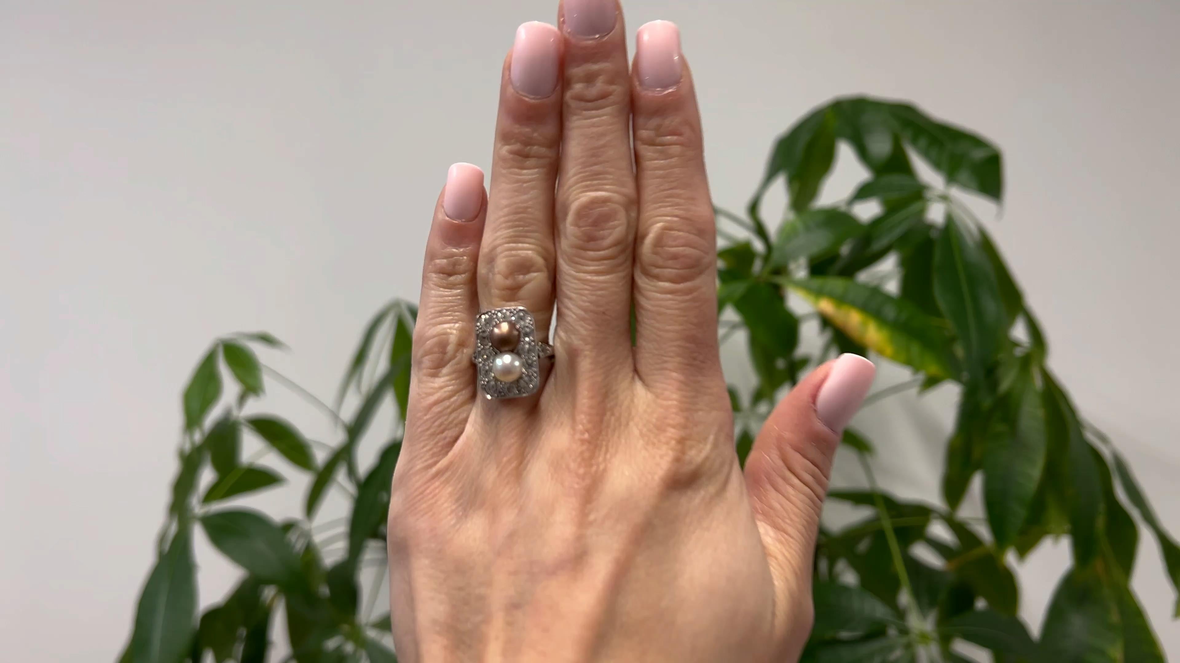 One Edwardian Pearl and Diamond Platinum Ring. Featuring one cream and one brown pearl. Accented by 14 old mine cut diamonds with a total weight of approximately 2.00 carats, graded near-colorless, SI clarity. Crafted in platinum. Circa 1910. The