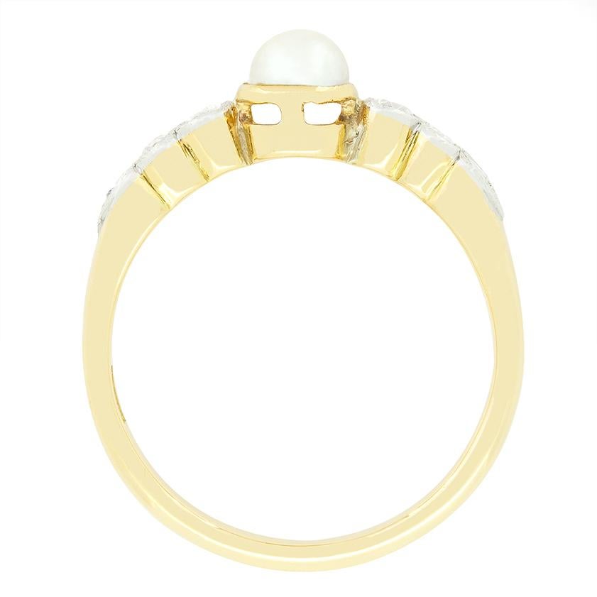 Daring back to the Edwardian era, this charming solitaire ring centres around a single natural pearl. The pear is 4.5mm in width and set upon an 18 carat yellow gold collet. Down each shoulder three old cut diamonds are rub over set into milgrained