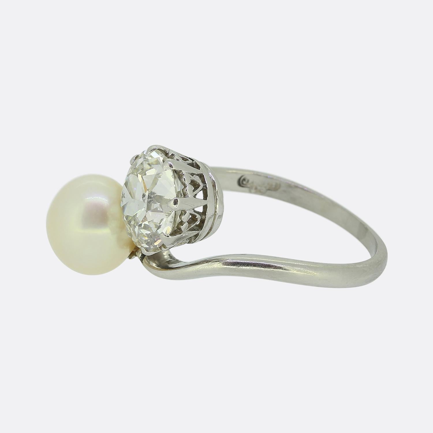 Nous avons ici une magnifique bague à deux pierres datant de la période édouardienne. Cette pièce ancienne présente une seule perle blanche lustrée arrondie et un seul diamant rond à facettes de taille européenne ancienne. La perle et le diamant