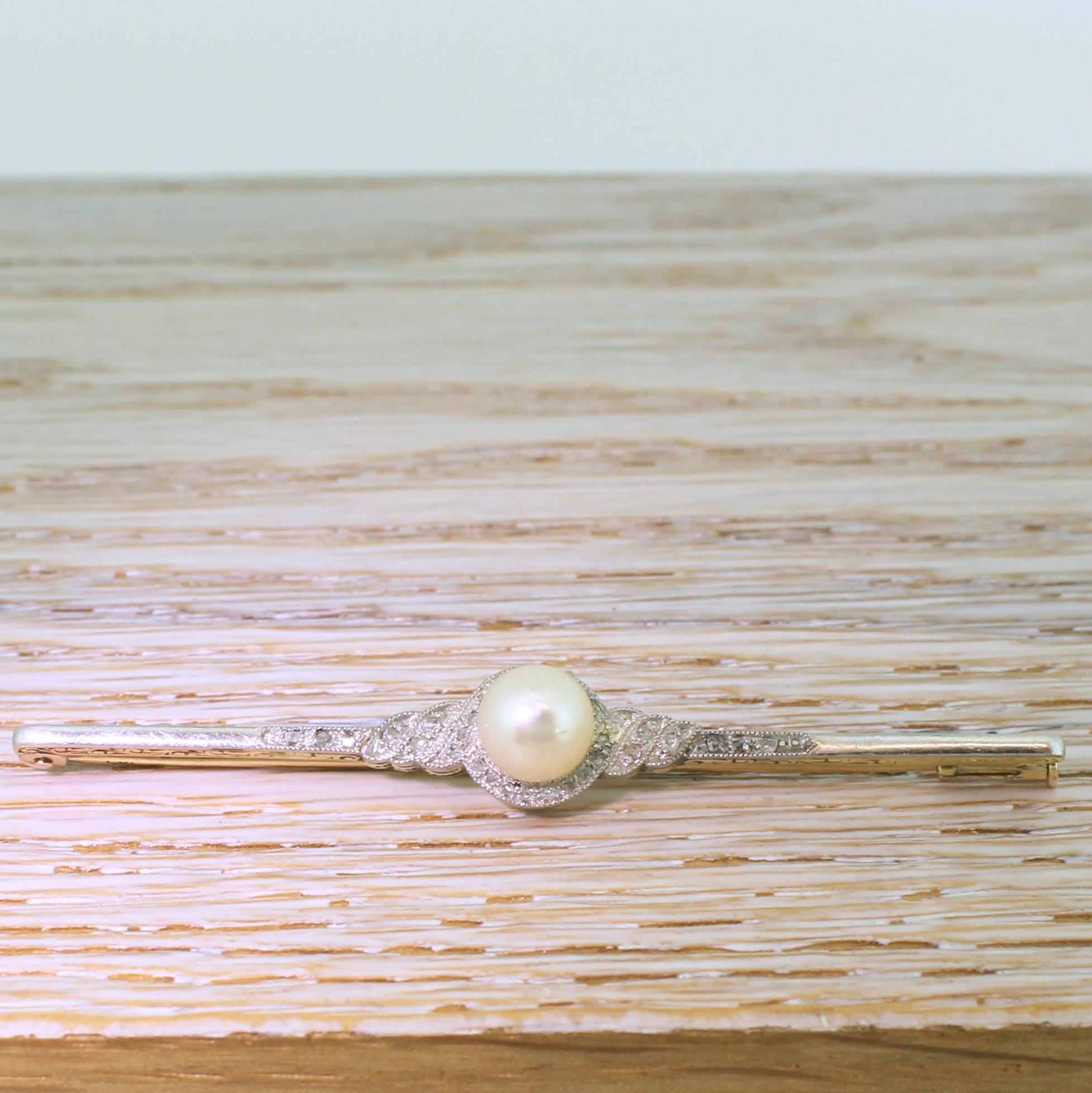 A delightfully elegant antique pearl pin. The cultured pearl in the centre is surrounded by a swirling border thirty-two rose cut diamonds set in platinum, backed in 18k yellow gold. Intricately engraving swirling detailing in the gallery adds