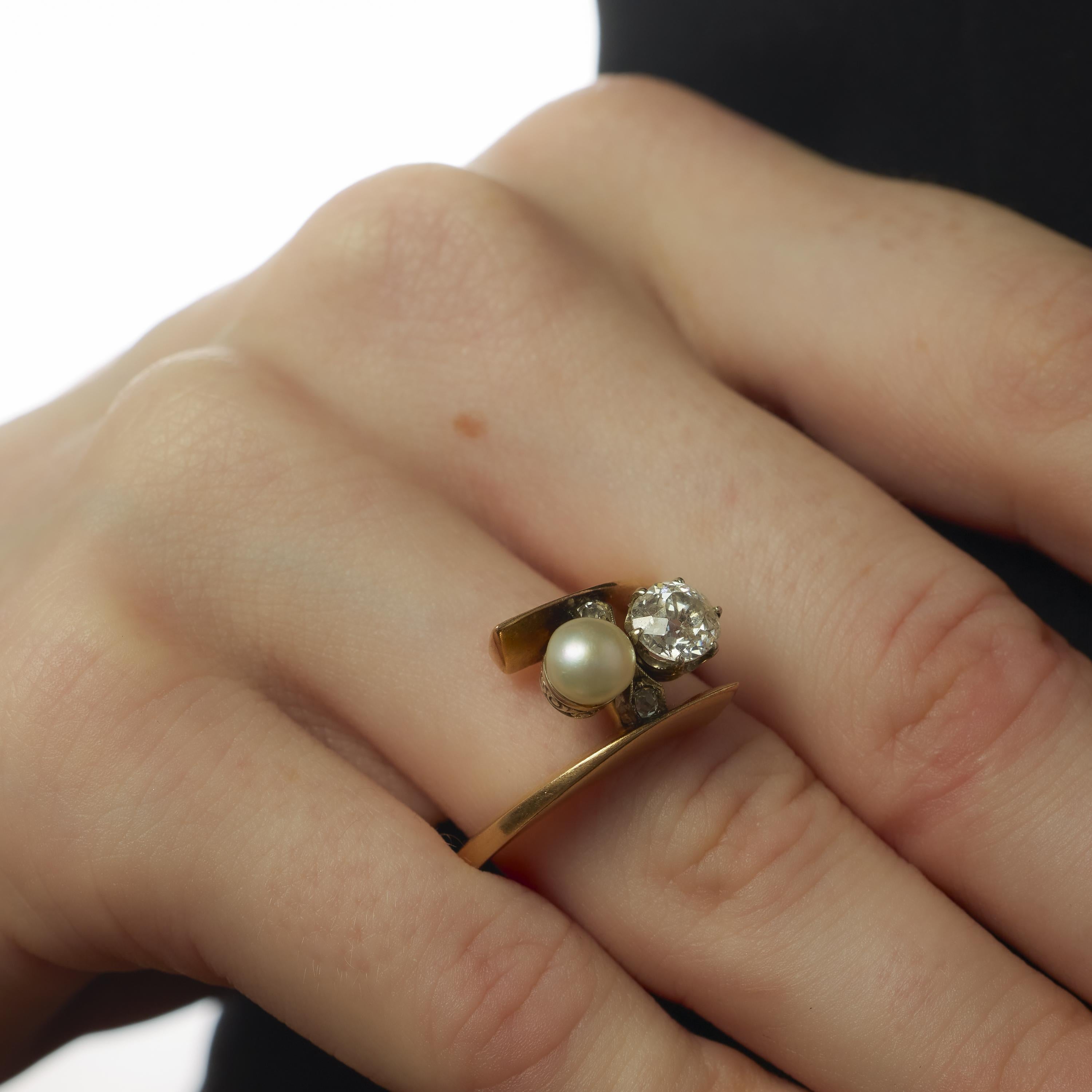 This Edwardian ring presents a refined composition centered around a 5.66 mm pearl, its soft luster complemented by the sparkle of a 0.95 carat old mine cut diamond. Two smaller old mine cut diamonds, totaling approximately 0.05 carats, add balance