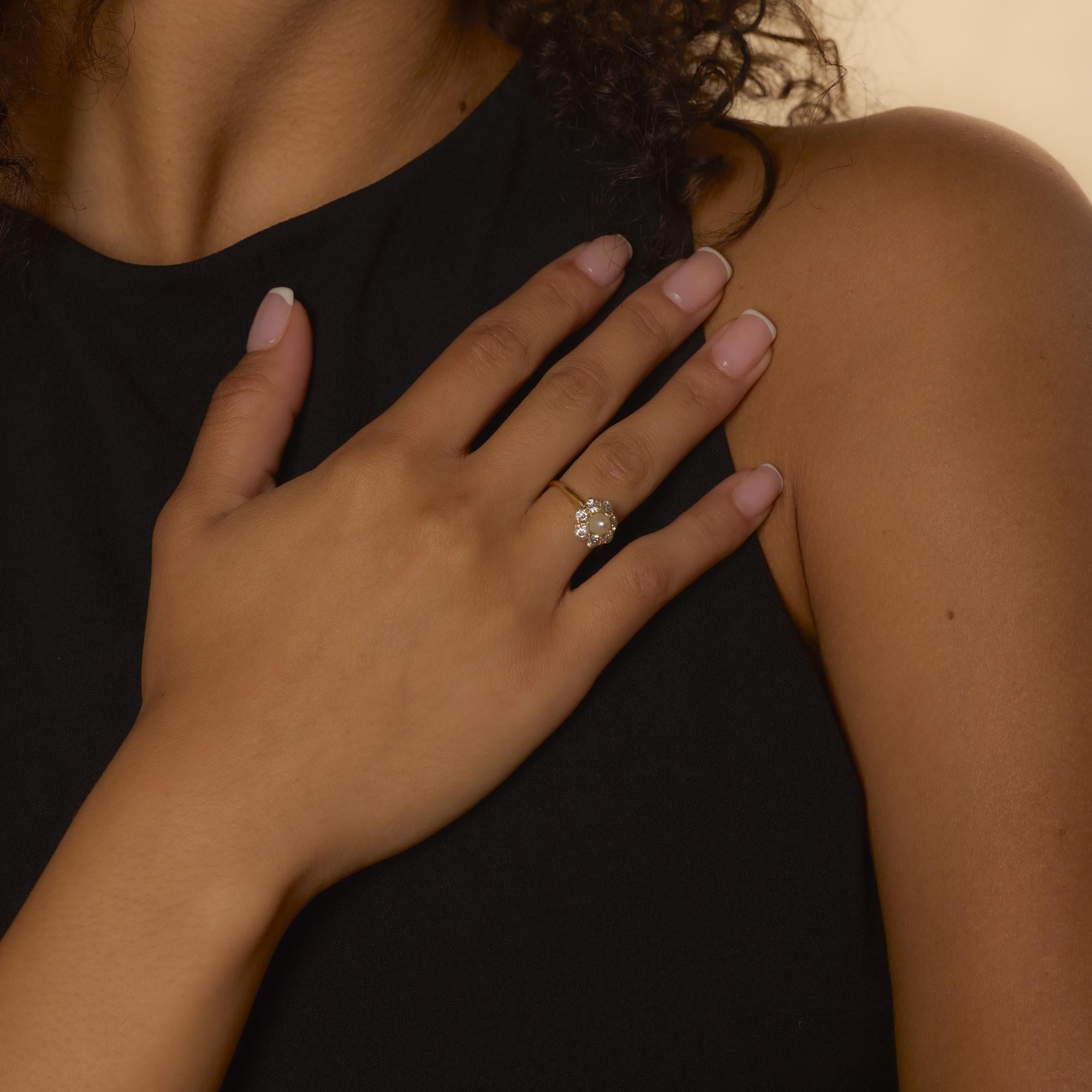 Cette bague de style édouardien présente une perle lumineuse encadrée par sept diamants antiques étincelants totalisant environ 1,15 carat, sertis dans un or jaune 18k chaleureux.