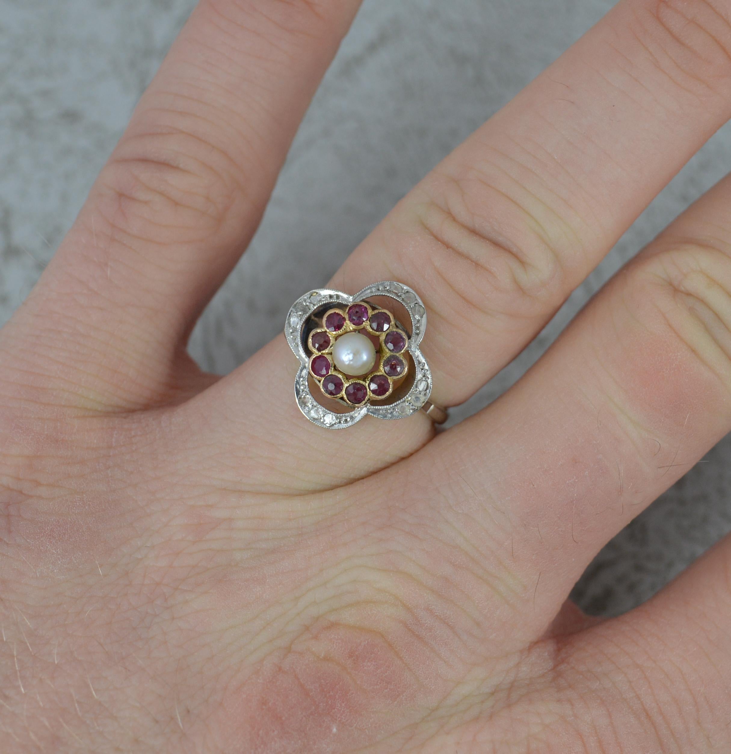A superb Edwardian period cluster ring.
Solid 18 carat white gold shank with yellow gold head and platinum setting.
Designed with a pearl to centre, 3.7mm diameter. Surrounding are ten round cut ruby stones in full bezel settings. To the outside are