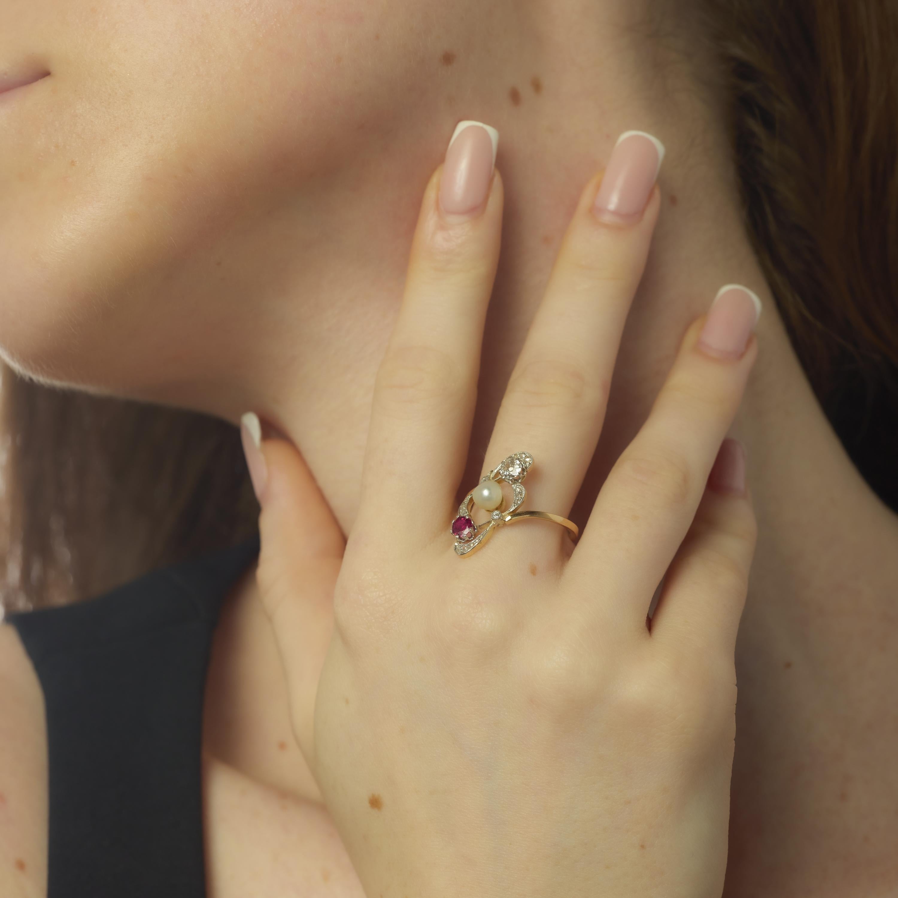 Cette bague de style Eleg dégage une élégance gracieuse avec sa perle centrale, mesurant environ 5,37 mm, qui brille doucement dans une monture finement ouvragée. Un rubis rond brillant d'environ 0,15 carat ajoute une touche de couleur riche, tandis