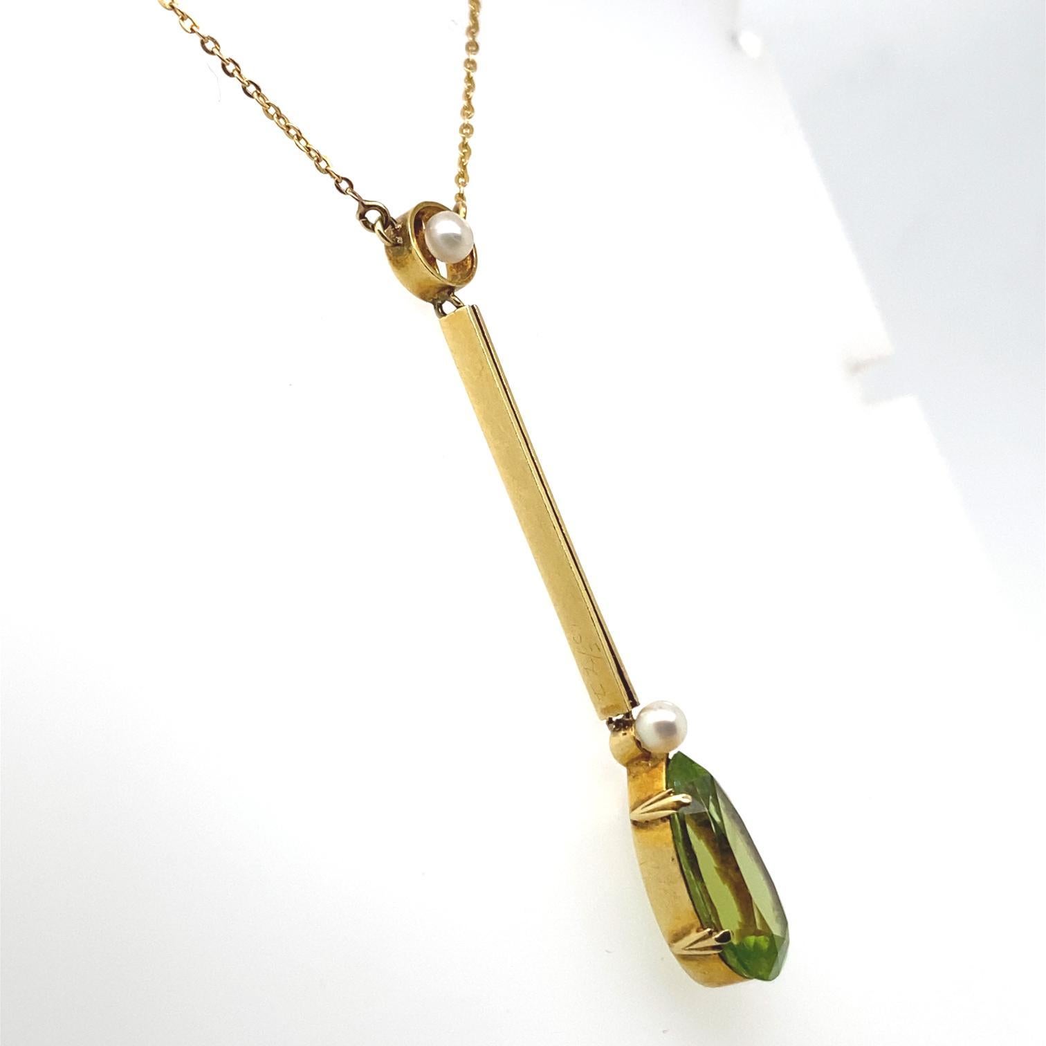 An Edwardian peridot and pearl pendant necklace in 15 karat yellow gold.

This sweet pendant is set to its centre with a seed pearl of 3mm within a 15 karat yellow gold circular frame, from which suspends a lively green pear cut peridot of 2.63