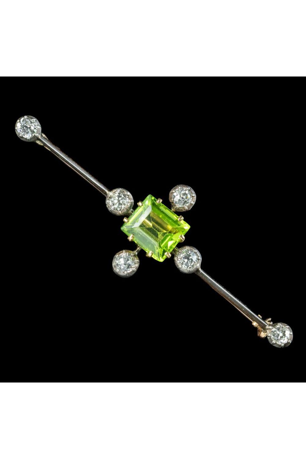 A fancy antique Edwardian bar brooch boasting a bright, green step cut peridot in the centre weighing approx. 3.5ct. It’s surrounded by four sparkling old European cut diamonds and an additional one on each end of the bar. They weigh approx. 0.20ct