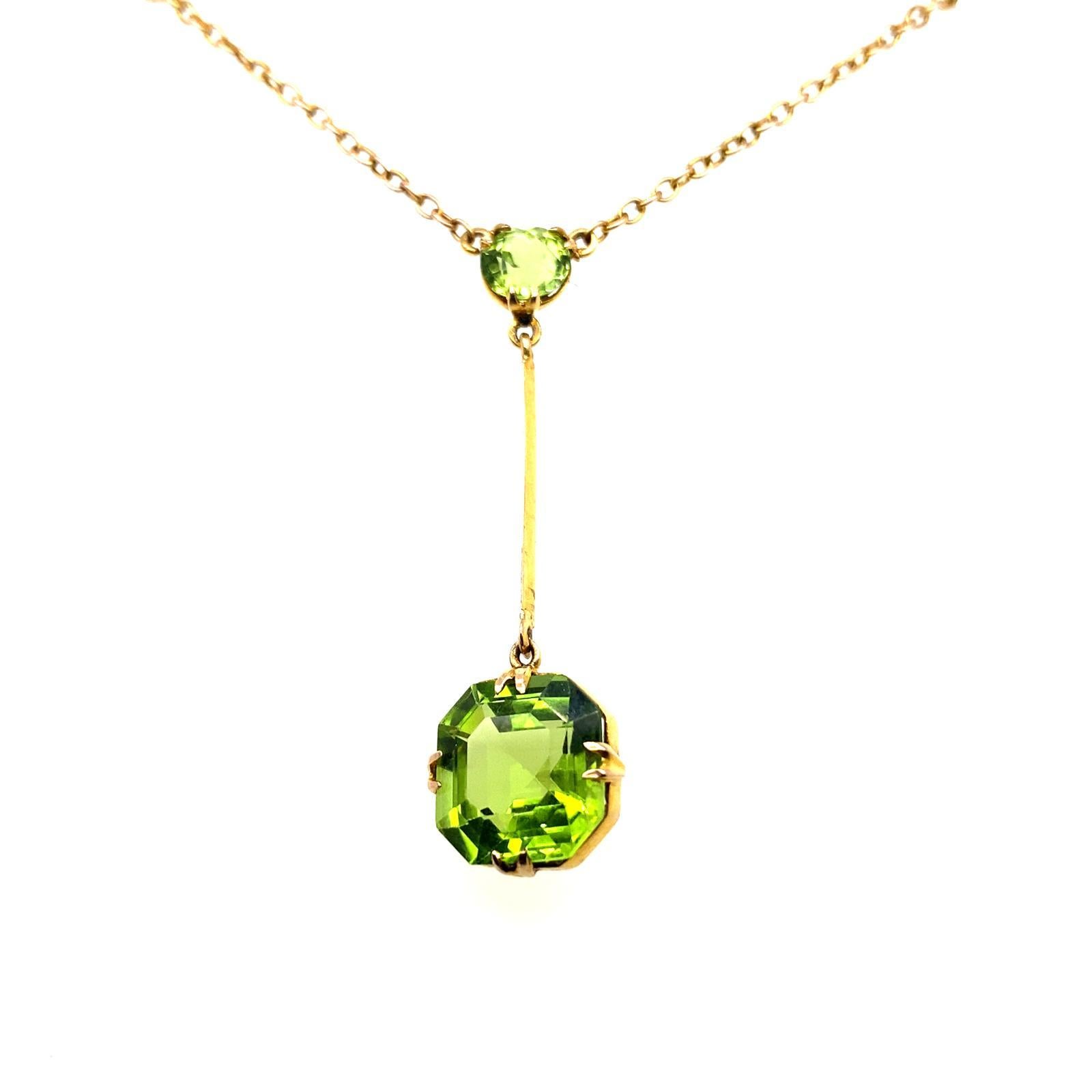 An Edwardian Peridot Pendant Necklace in 9 Karat Yellow Gold.

This pretty pendant is set to its centre with a round cut periodot of 0.95 carats approximately within a claw setting from which suspends a larger lively green square cut peridot of 4.97