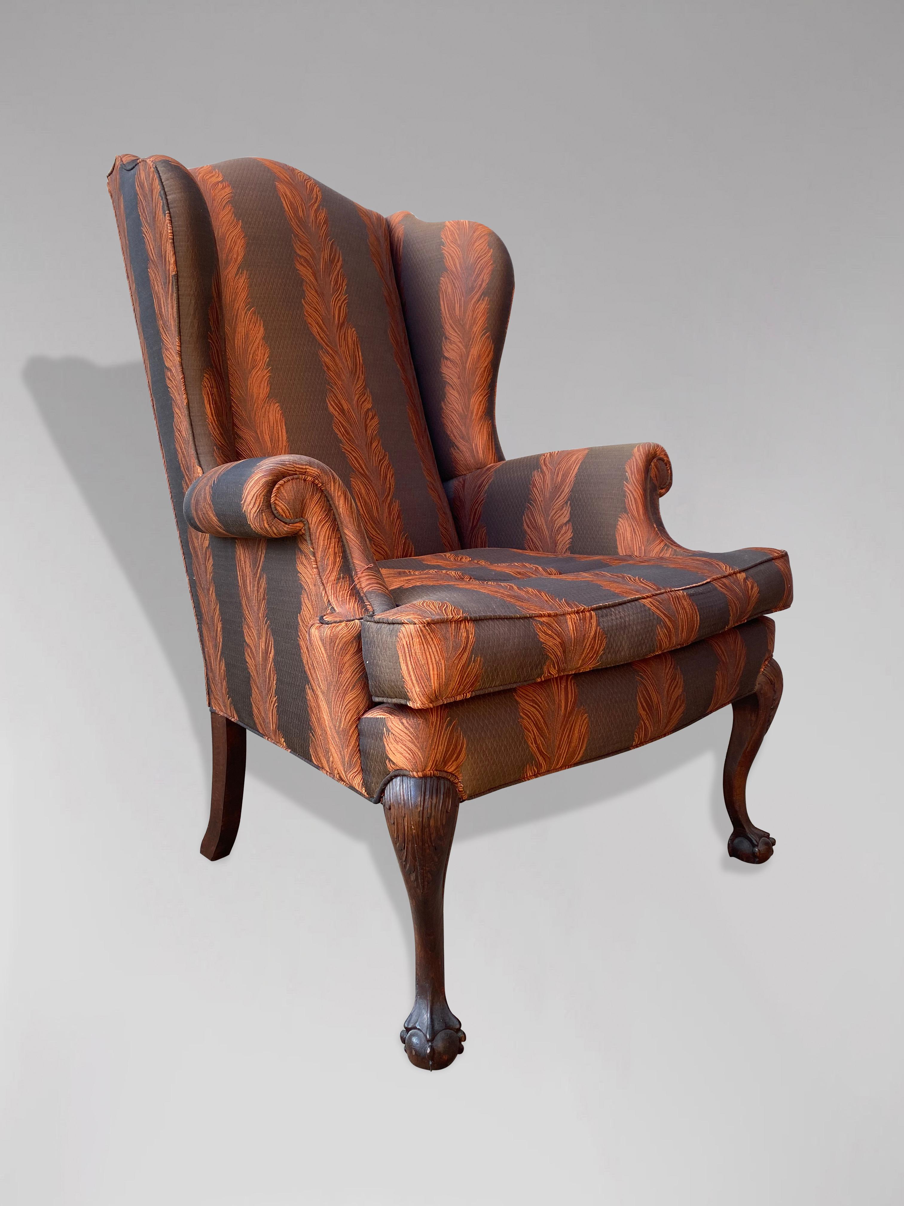An early 20th century Edwardian period newly reupholstered wing armchair with loose feathered cushion, standing on mahogany carved cabriole legs ending on claw and ball feet. All recently fully reupholstered in a quality fabric. Very comfortable.