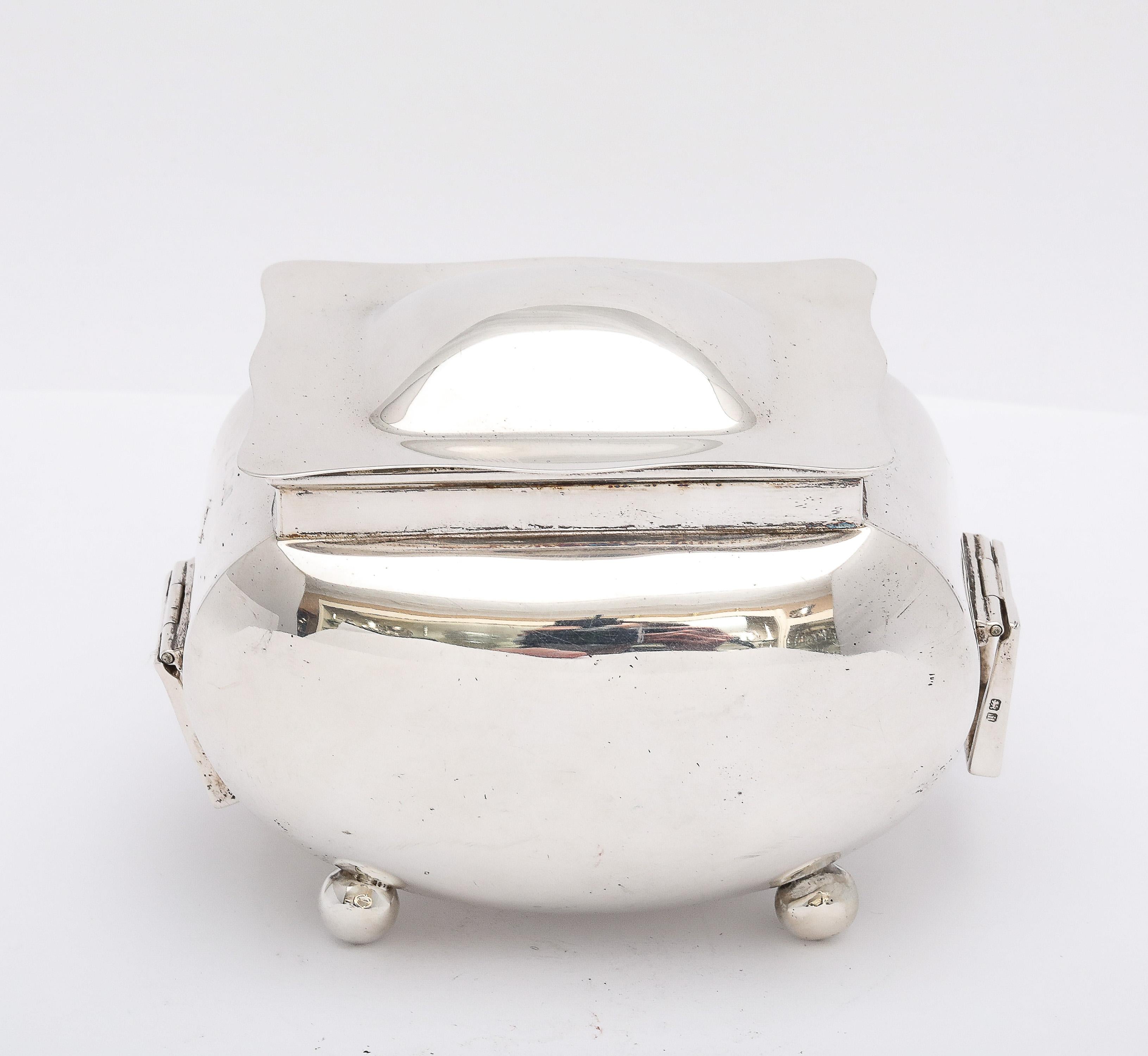 Edwardian Period, sterling silver tea caddy on ball feet, and having a hinged lid and hinged, movable handles. Lovely, clean lines. Measures 3 inches high (at highest point)  x approximately 4 1/4 inches wide (from outer edge of each hinged, movable