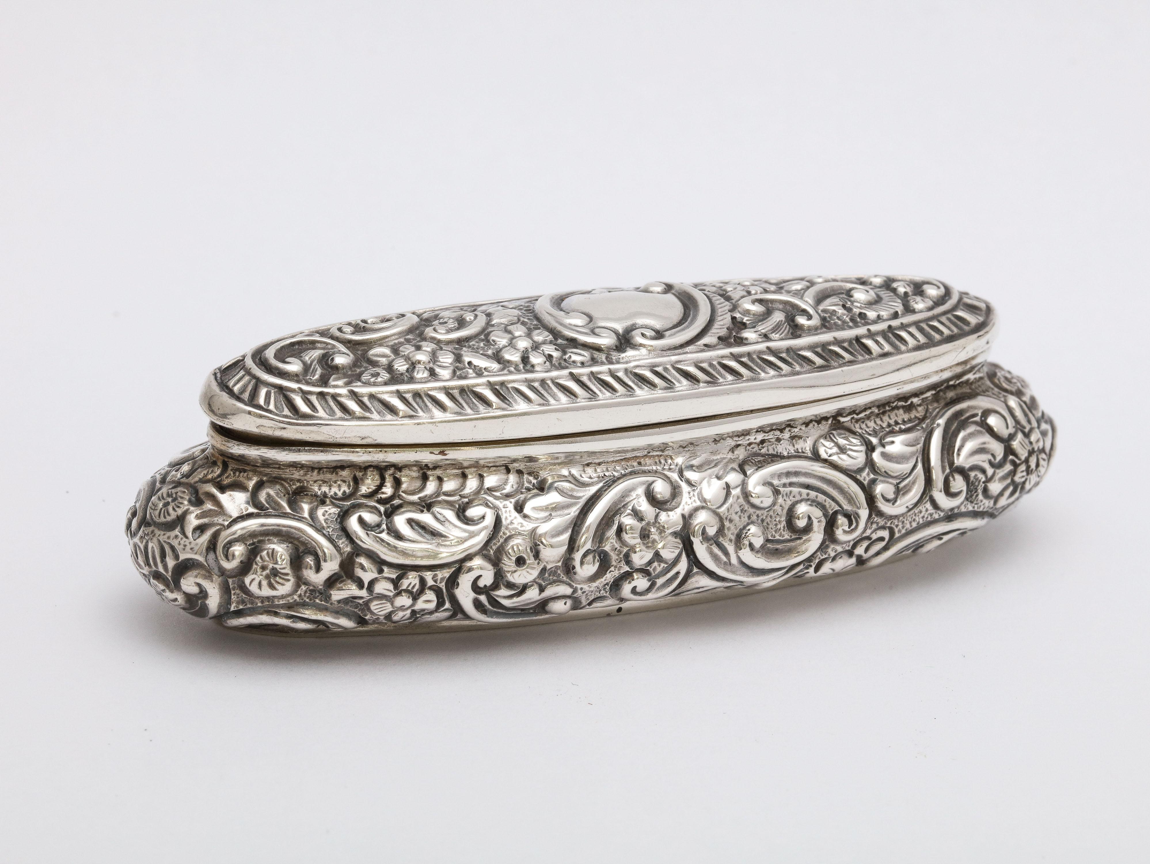 Edwardian period, sterling silver, oval trinkets box with hinged lid, London, 1913, Charles James Fox - maker. Measures 4 inches wide x 1 1/4 inches deep x 1 1/4 inches high. Weighs 1.185 troy ounces. Interior in gilded. vacant cartouche. Some very