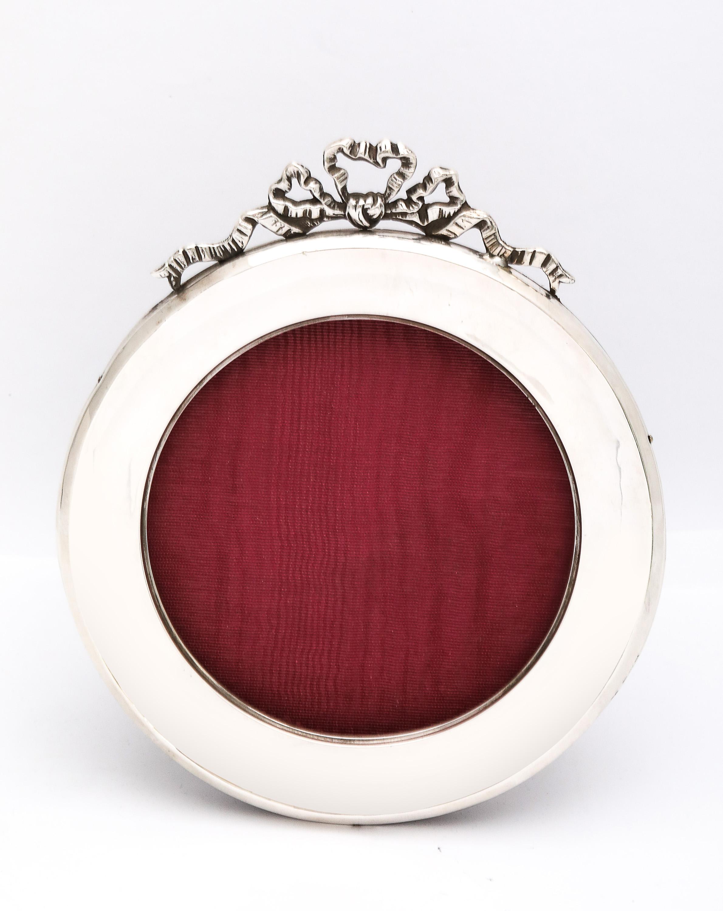 Cornice rotonda in argento sterling del periodo edoardiano, con retro in legno e fiocco finale, Birmingham, Inghilterra, con marchio dell'anno 1914, Charles S. Greene & Company - produttori. Misura oltre 5,5 pollici di diametro x 6,1/4 pollici di