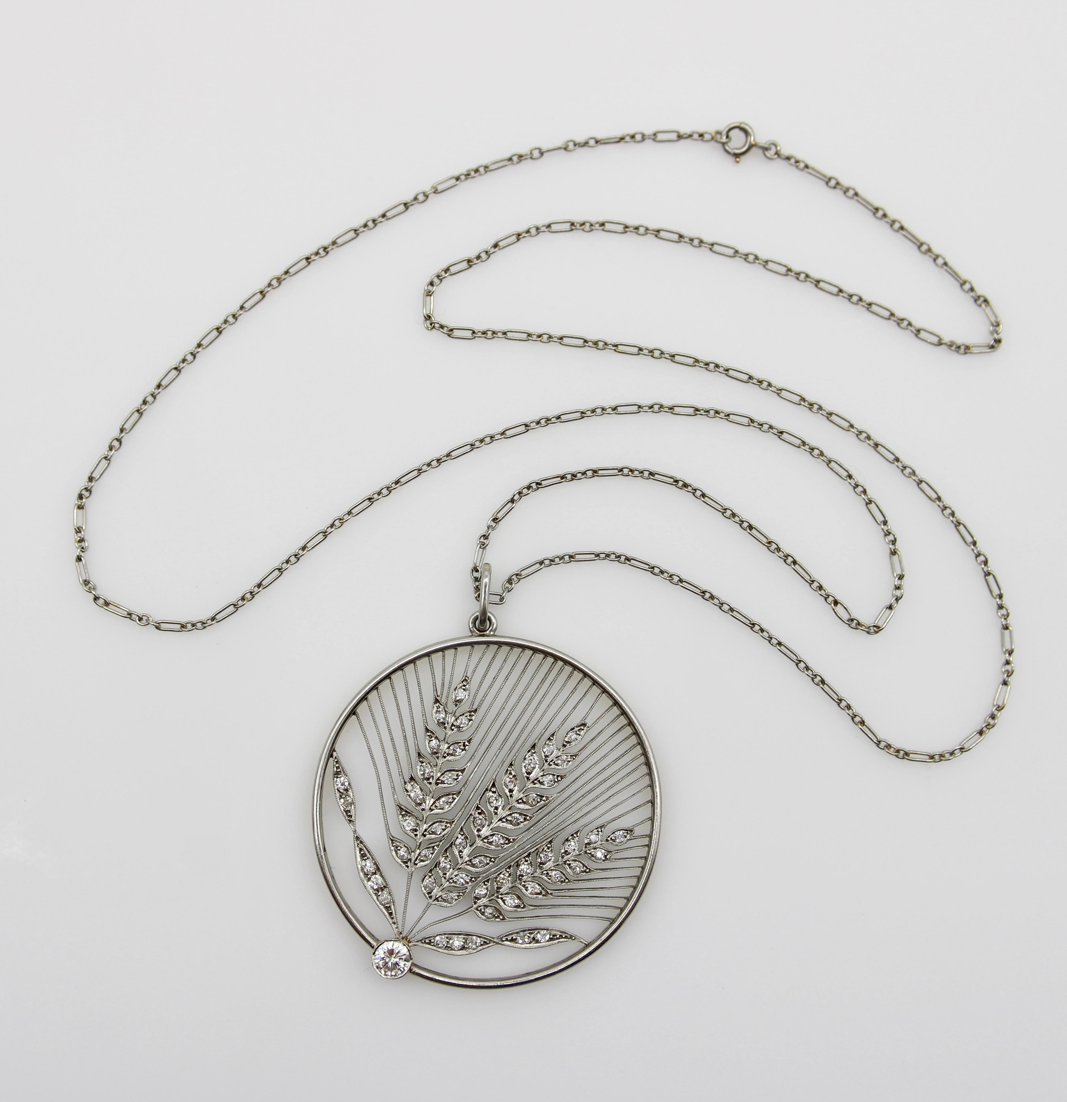 Ce superbe pendentif médaillon de style édouardien est réalisé en platine et présente trois gerbes de blé. Derrière eux, une cascade de très fines lignes de platine confère à la pièce une beauté évocatrice. Le blé est incrusté de diamants anciens