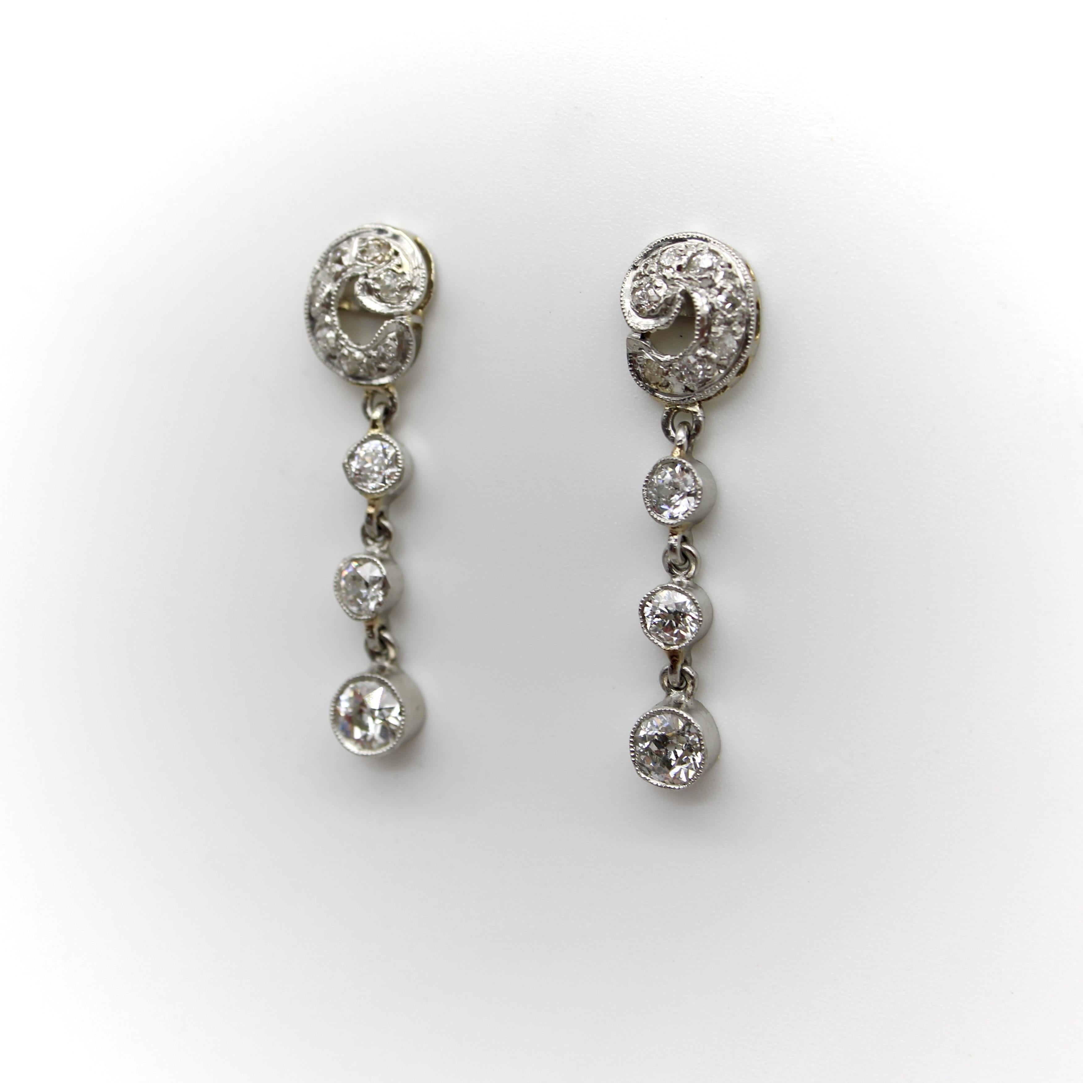 Ces boucles d'oreilles édouardiennes en platine sont ornées de diamants anciens et pendent joliment à l'oreille. Le haut de la boucle d'oreille est un feuillage enroulé qui a été sculpté et qui abrite sept diamants taille unique et taille Old Mine.