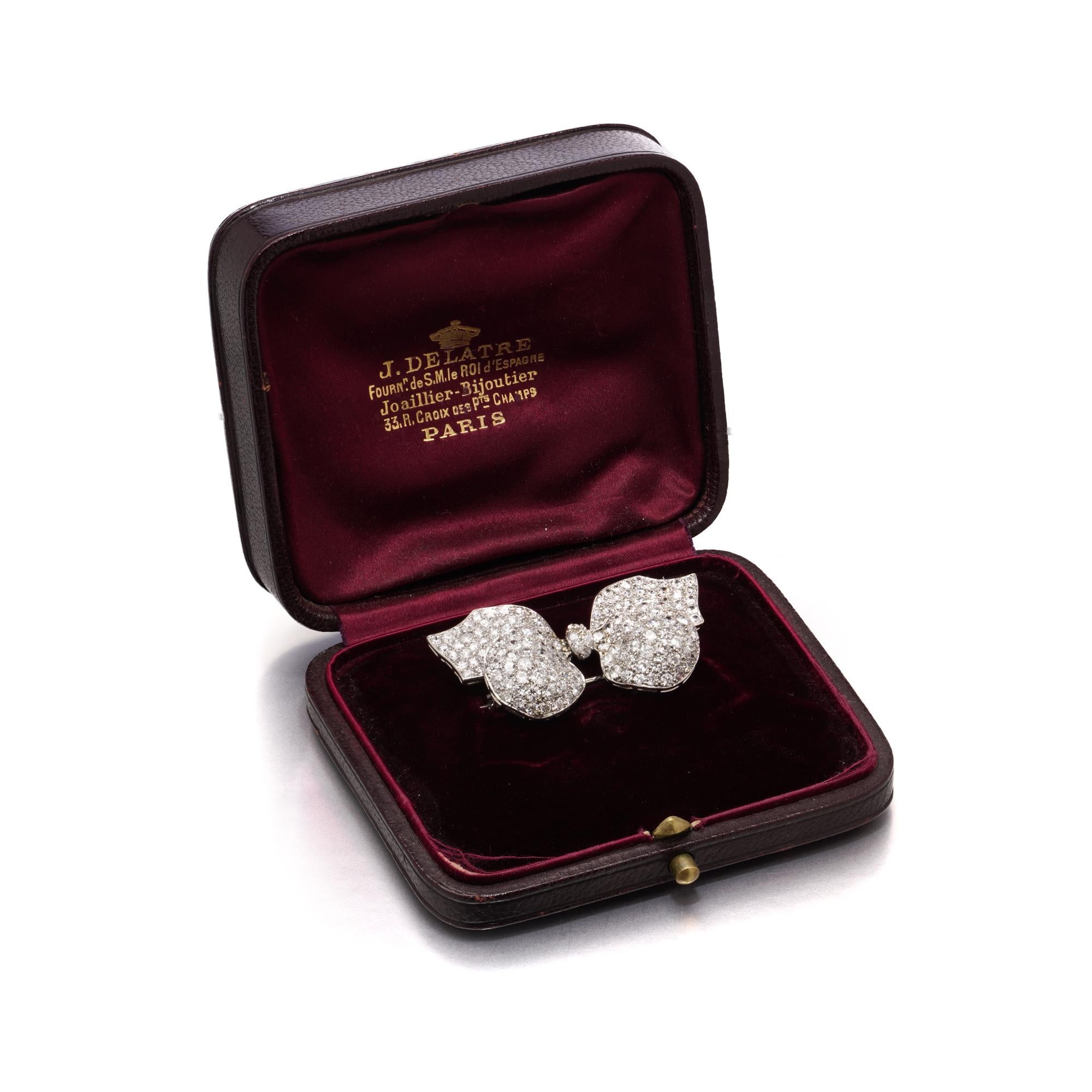 This elegant Edwardian brooch is crafted in platinum and formed as a stylised ribbon bow. The curving loops and flowing tails are pavé-set throughout with old European cut diamonds, designed to reflect light from every angle. The openwork structure