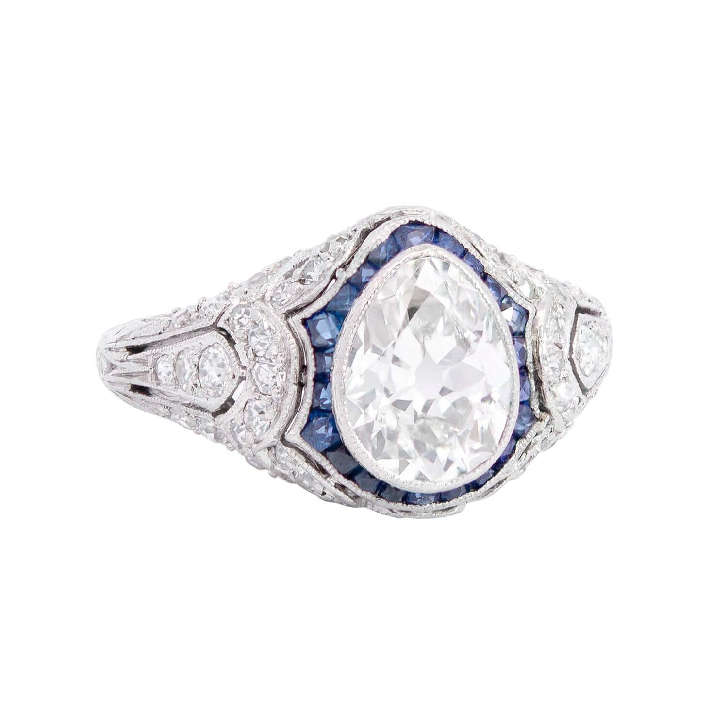 A gorgeous diamond and sapphire engagement ring from the Edwardian (ca1910) era! 

Crafted in platinum, this stunning piece holds a beautiful old Mine Cut diamond at its center, encircled by a row of fabulous rich blue calibrated sapphires. 

The